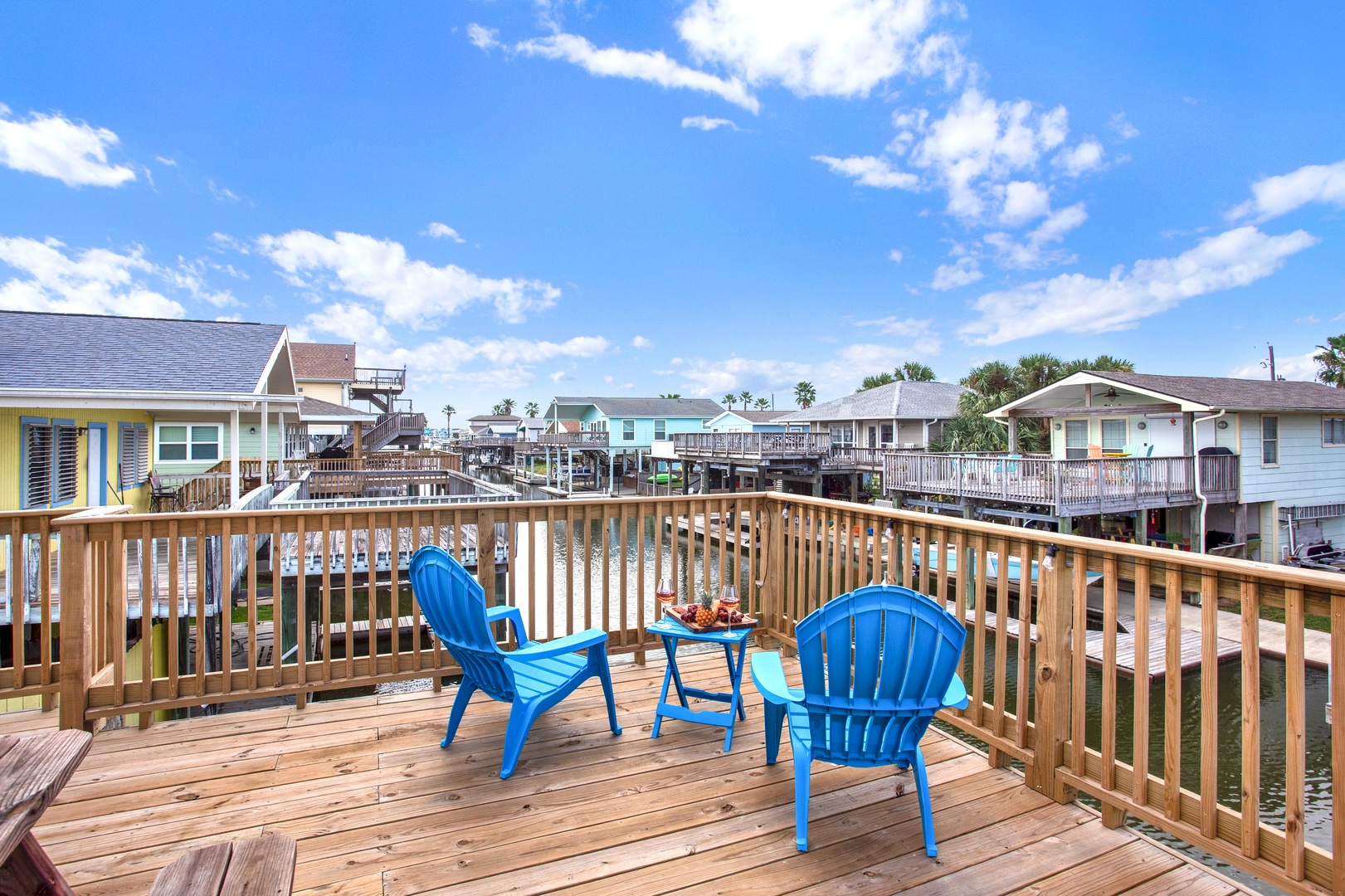 A spacious wooden deck with bright blue Adirondack chairs invites you to soak up the coastal sunshine and enjoy the peaceful canal views with your morning coffee.
