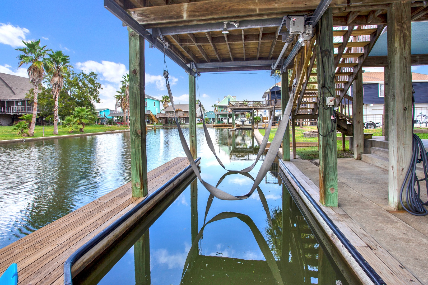 Private boat lift and dock on a peaceful canal, with colorful waterfront homes and palm trees adding to the coastal charm of your retreat.