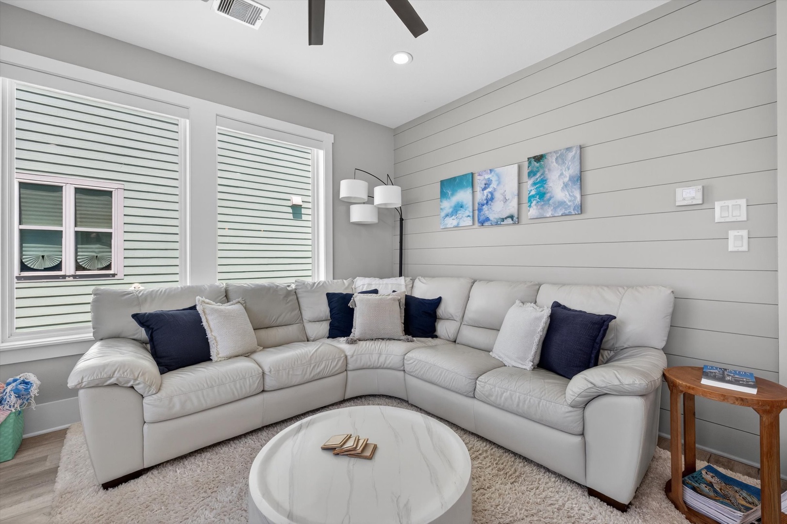 Coastal living room with sectional, shiplap, and sunlight.
