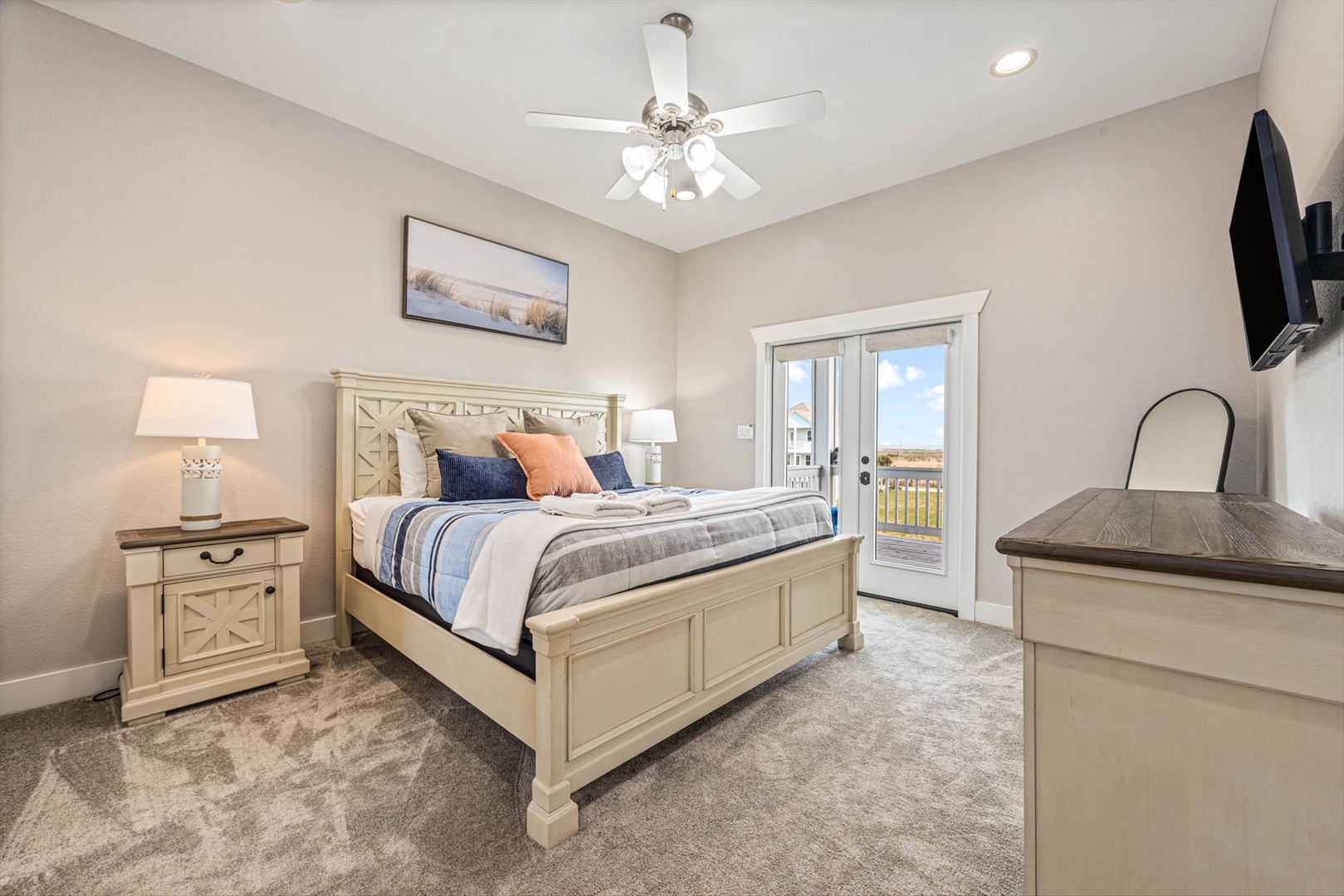 Primary upstairs bedroom with coastal bed and private balcony.