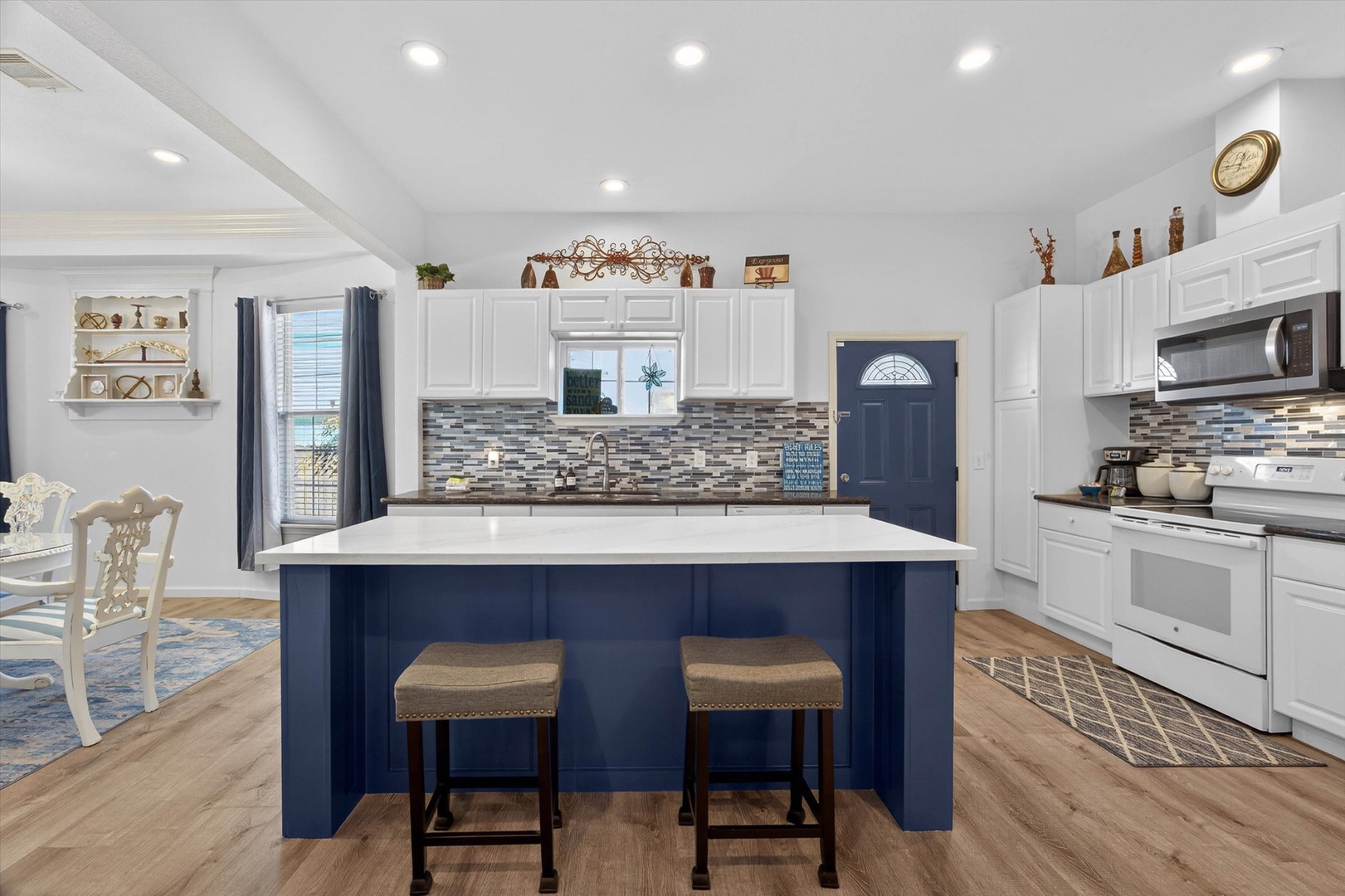 Cook your favorite meals in this spacious kitchen featuring a stunning navy island, white cabinetry, and modern appliances.