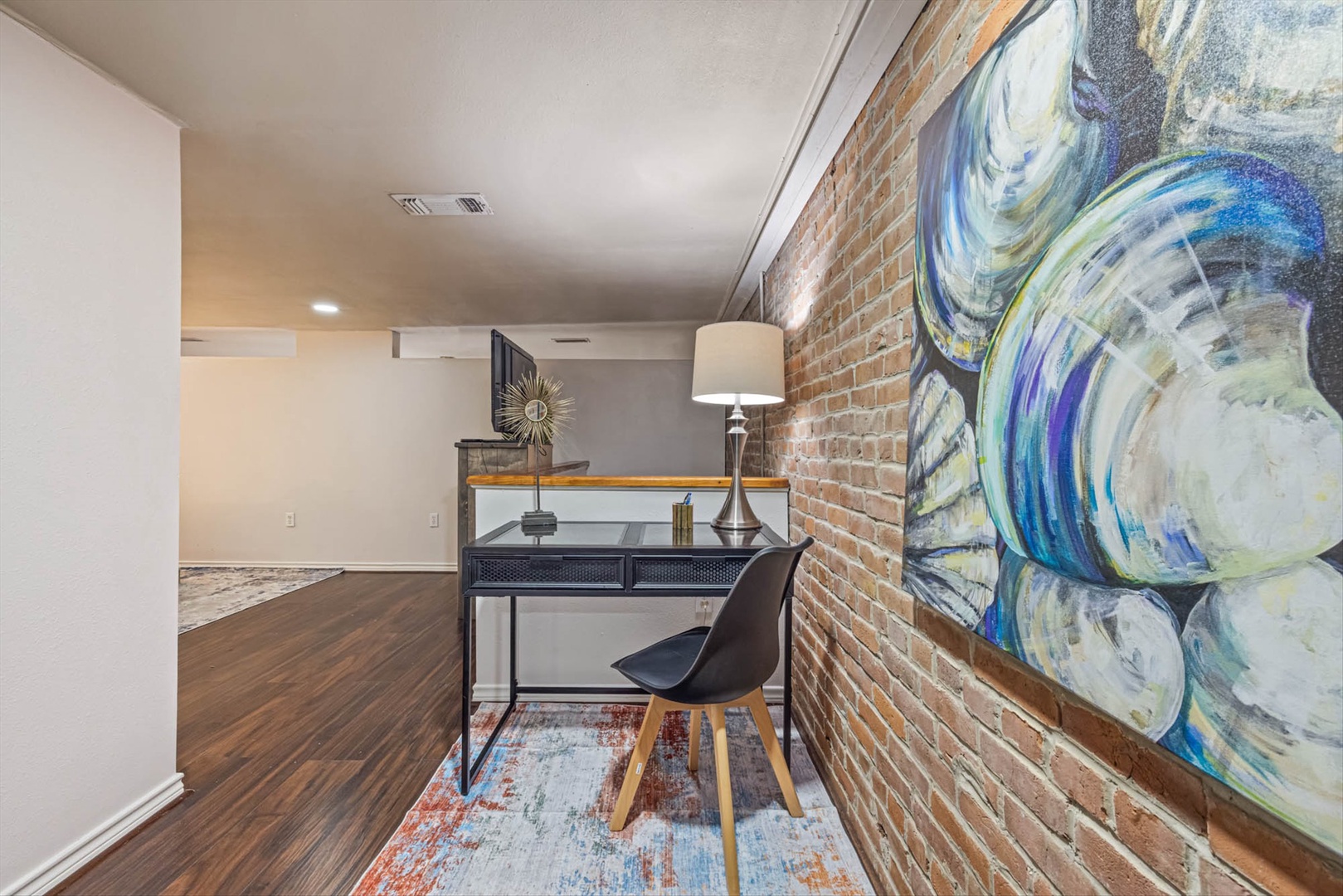 Work at a desk in a space with brick walls and art.