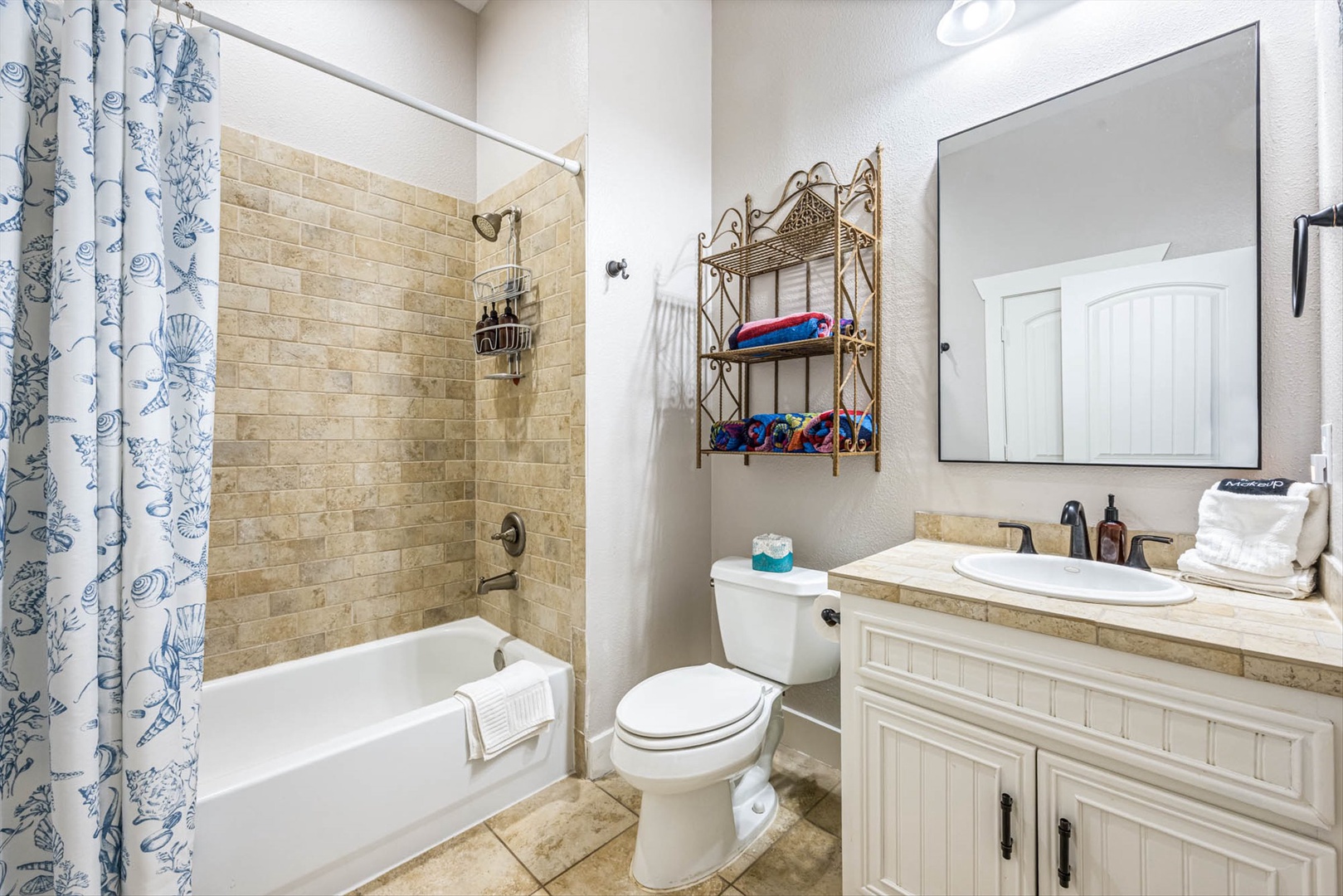 Relaxing bath with tub-shower combo and coastal décor.