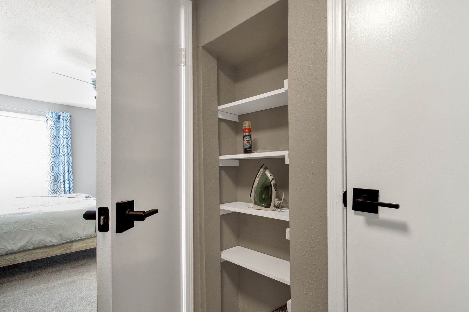 Private storage closet with shelves and iron.