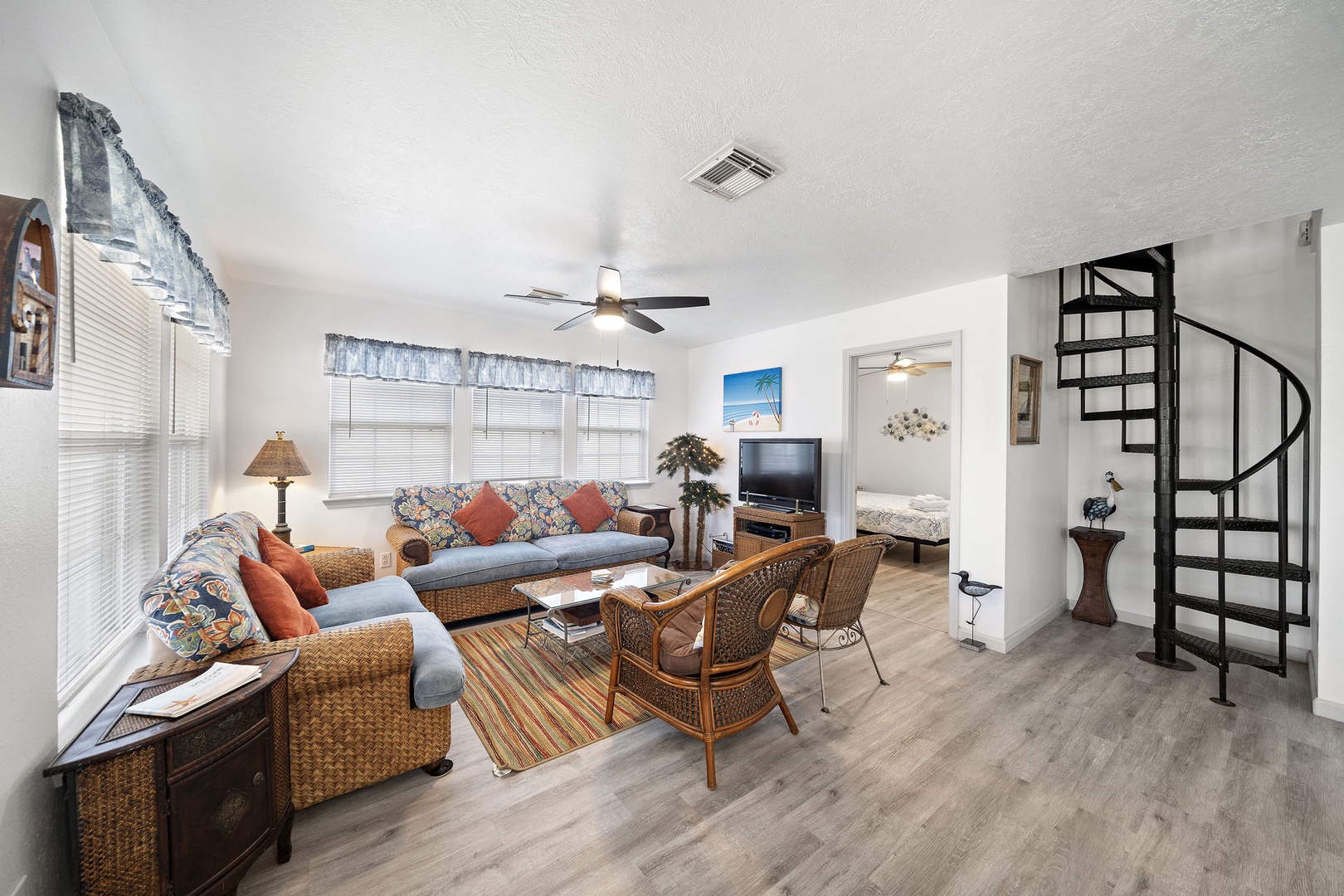 The soft sofa and wicker chairs invite you to relax, 2 bedrooms are off the living area, downstairs shared bath, and the spiral staircase leads to your private loft retreat.