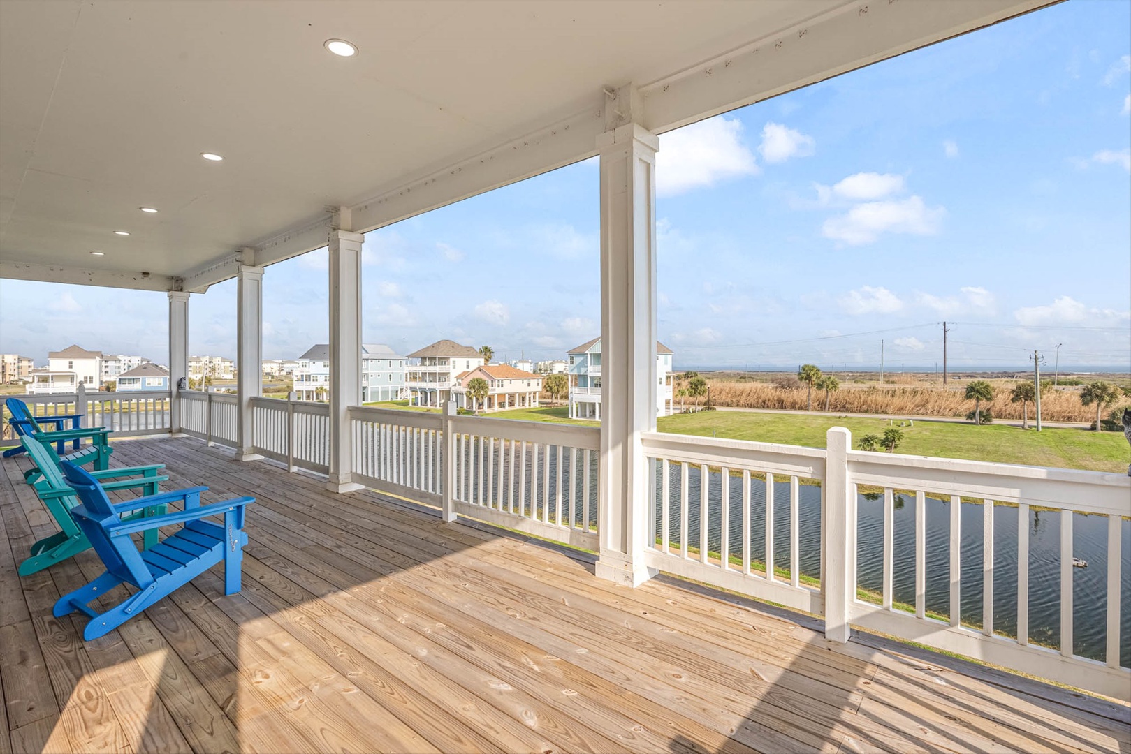 Covered deck with blue Adirondack chairs and coastal views.
