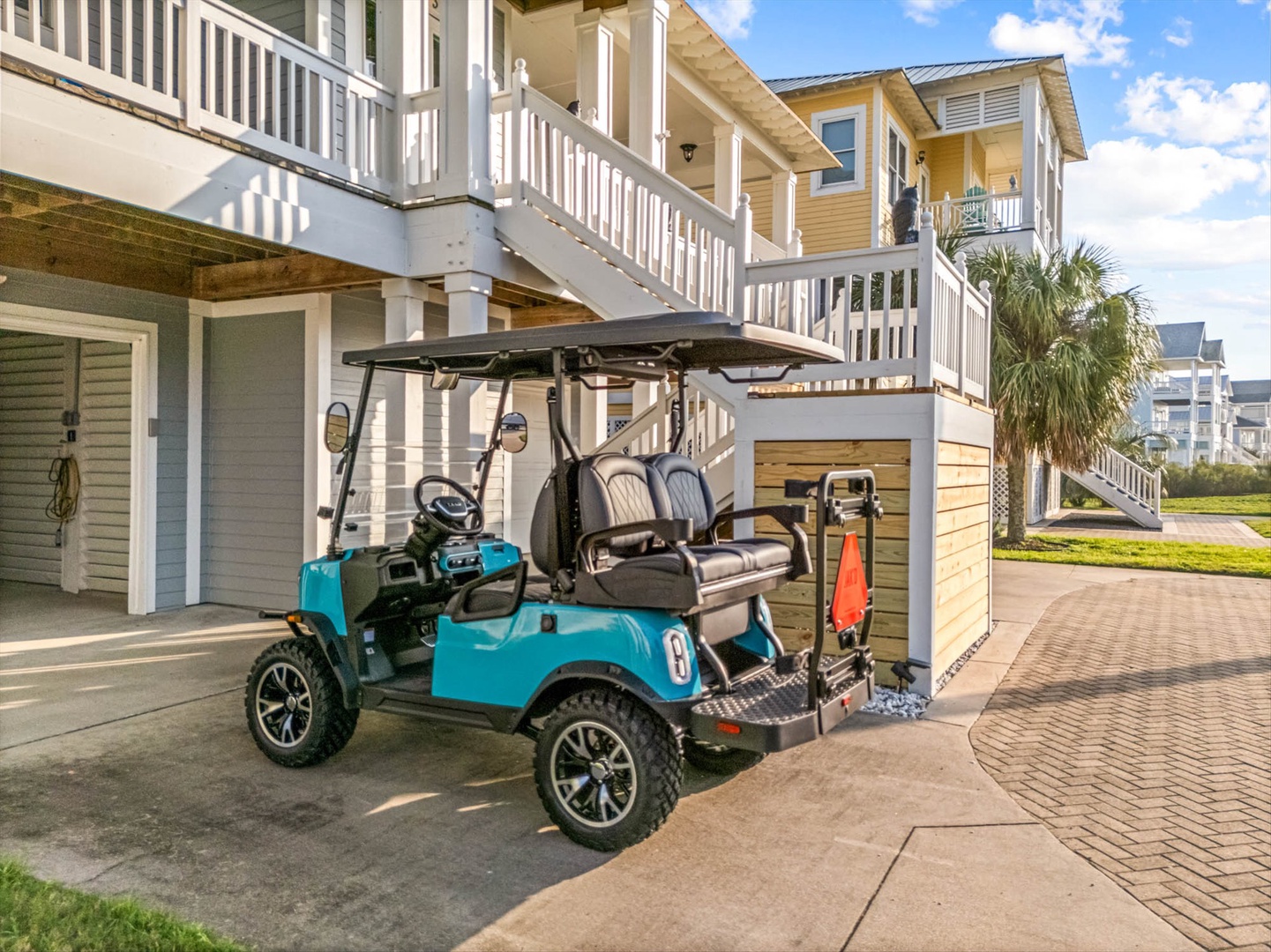 Golf cart parked at a coastal vacation rental with elevated walkways and tropical landscaping in a beach community.