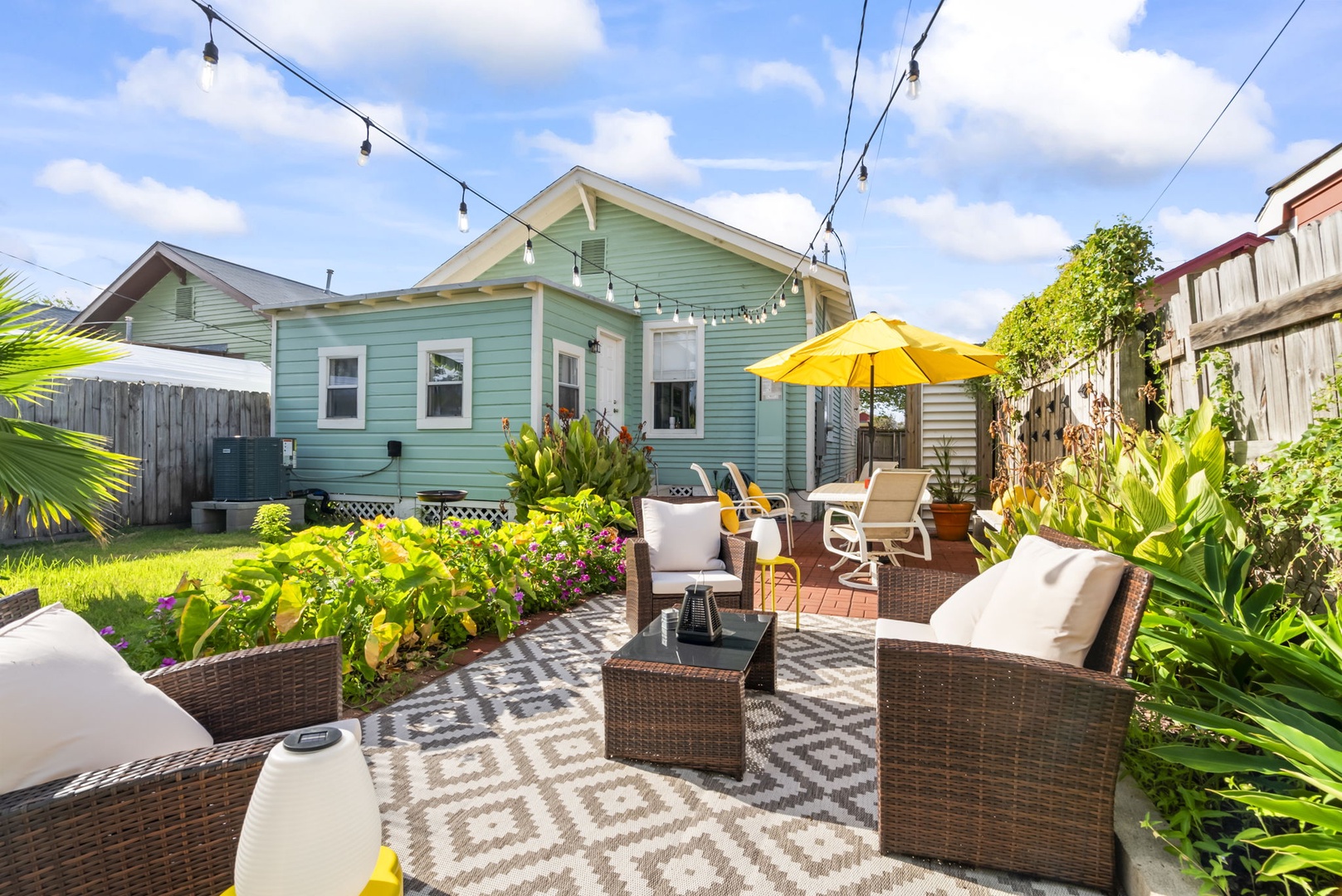 Tropical patio with seating, garden views, and string lights.