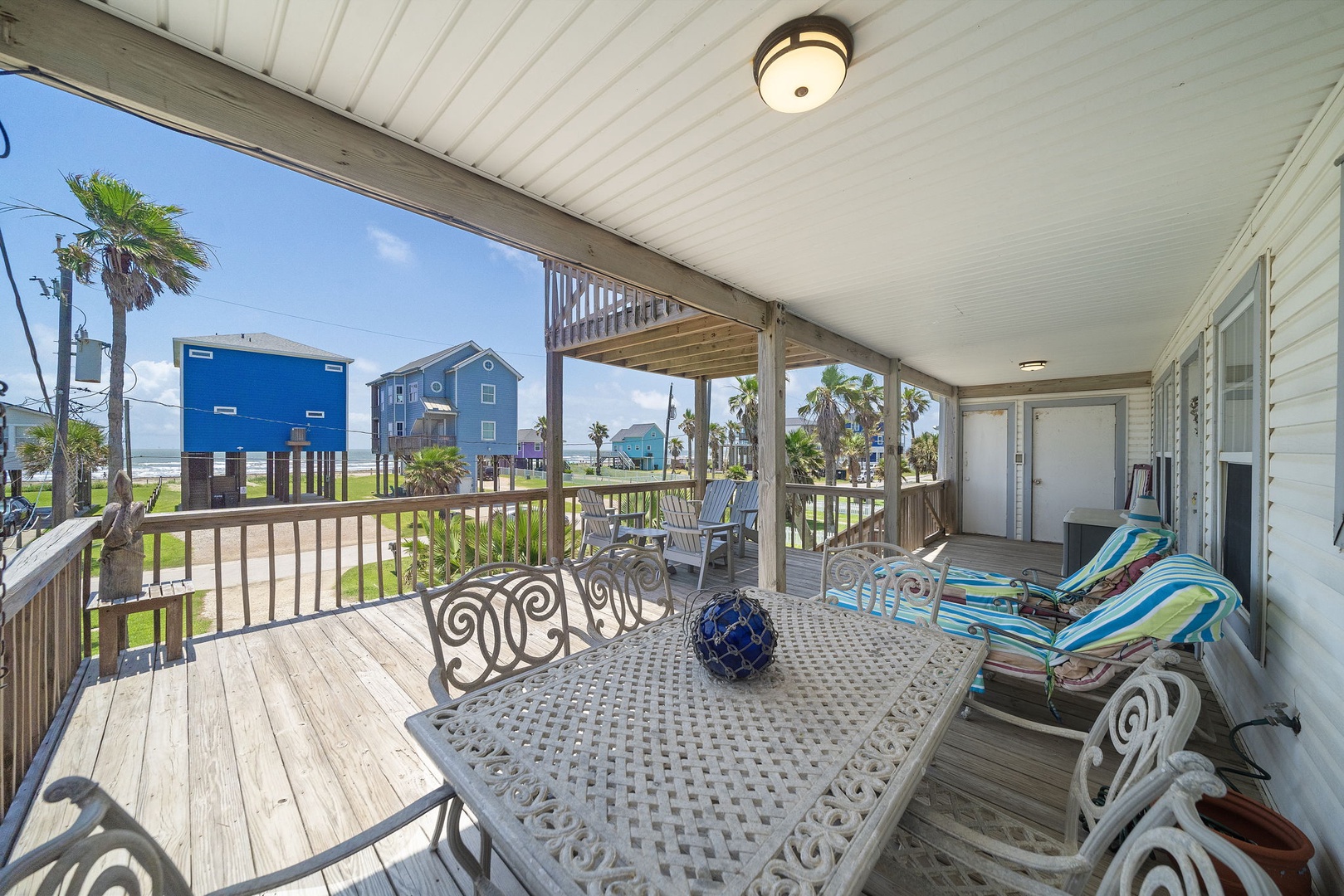 Relax on your spacious covered porch with ocean breezes and colorful coastal views. Sip morning coffee at the outdoor dining table or unwind in the lounge chairs as palm trees sway nearby.
