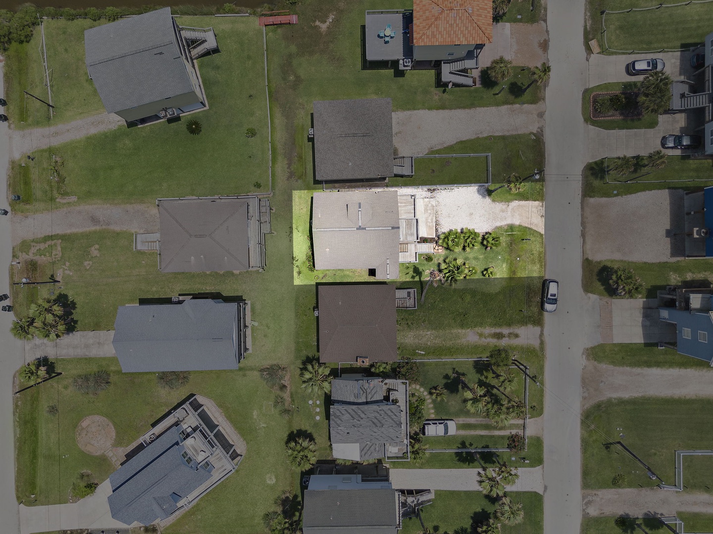 Take in the sweeping bird's-eye view of your peaceful residential neighborhood, where your charming vacation home sits nestled among lush green lawns and mature palm trees.