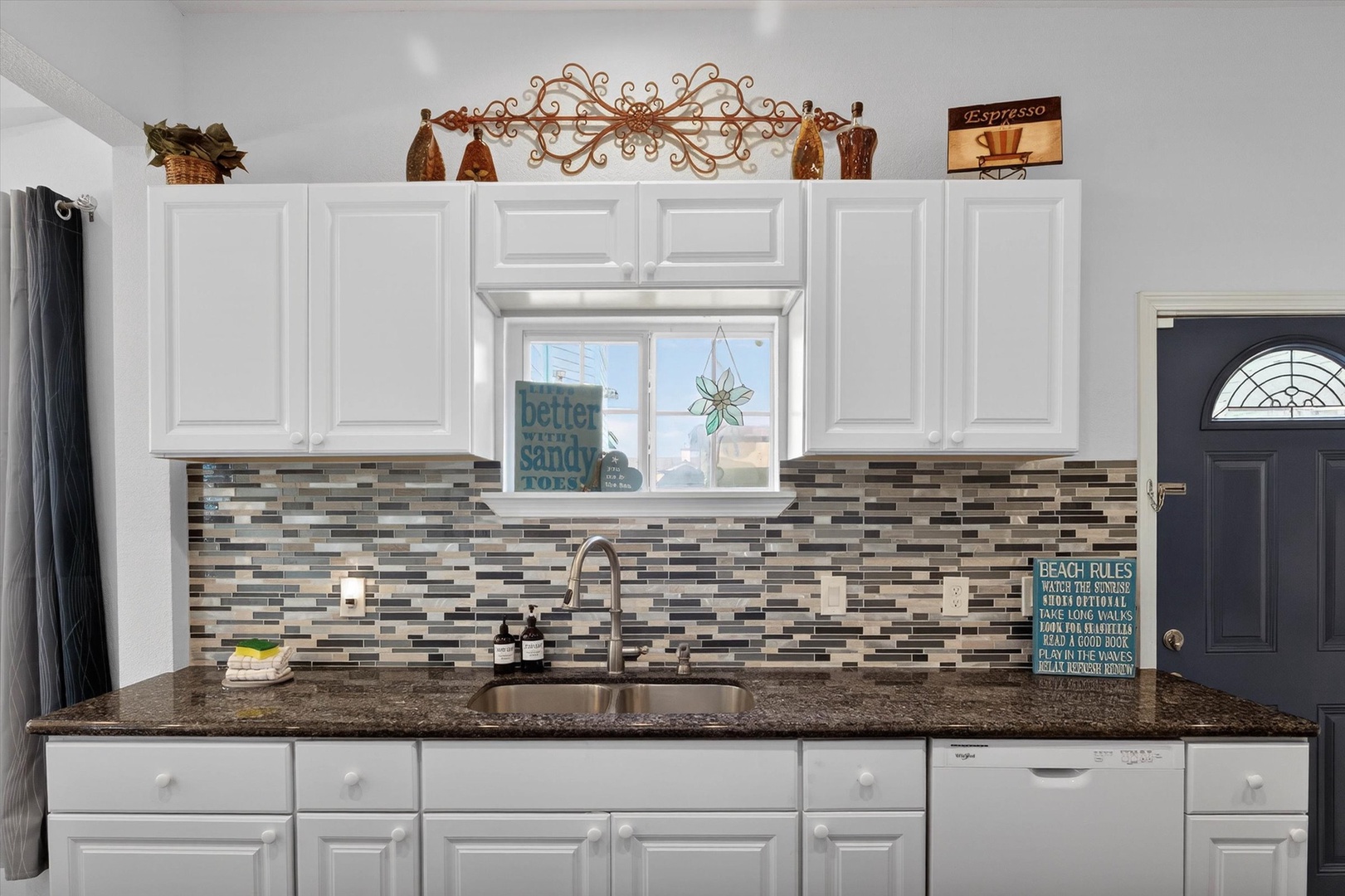 Your fully equipped kitchen features granite countertops, stylish tile backsplash, and charming beach-themed decor to inspire your culinary adventures.