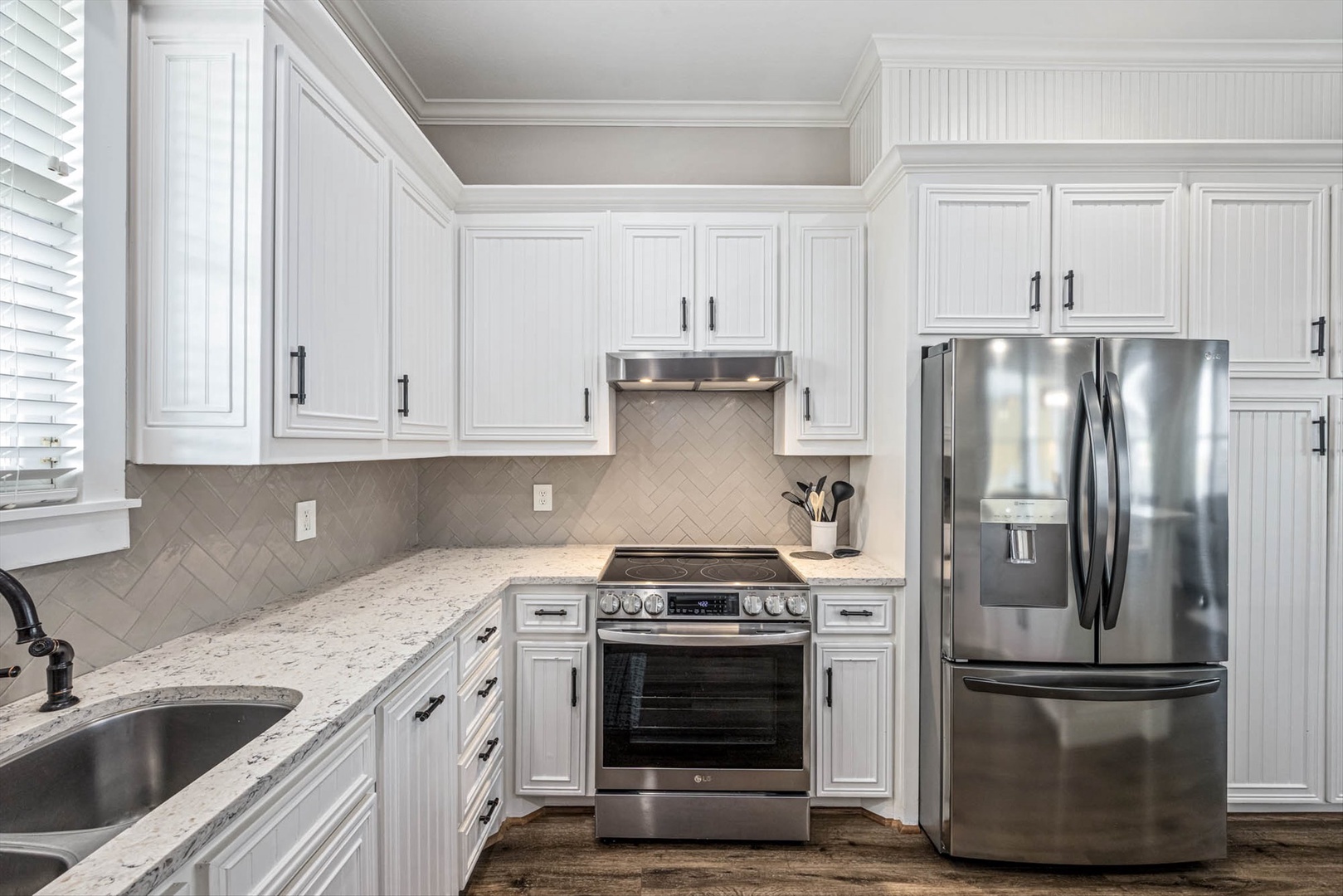 Fully equipped kitchen with white cabinets and marble counters.