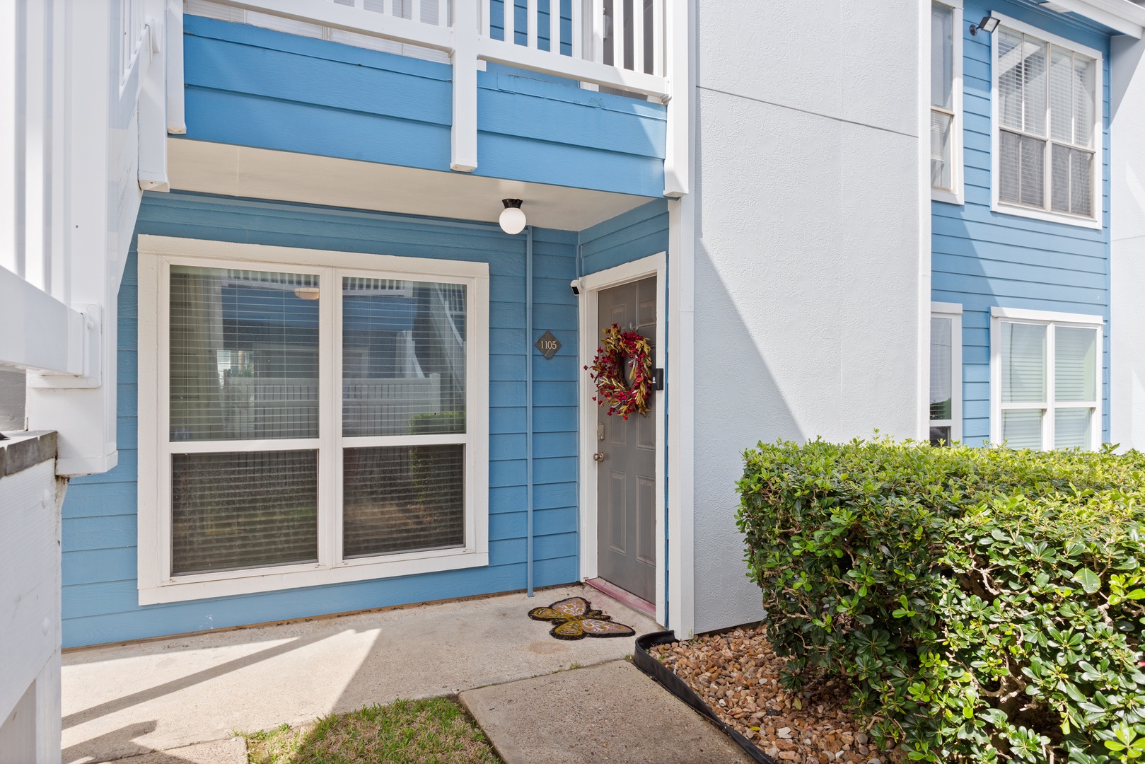 Charming blue townhome entrance with greenery