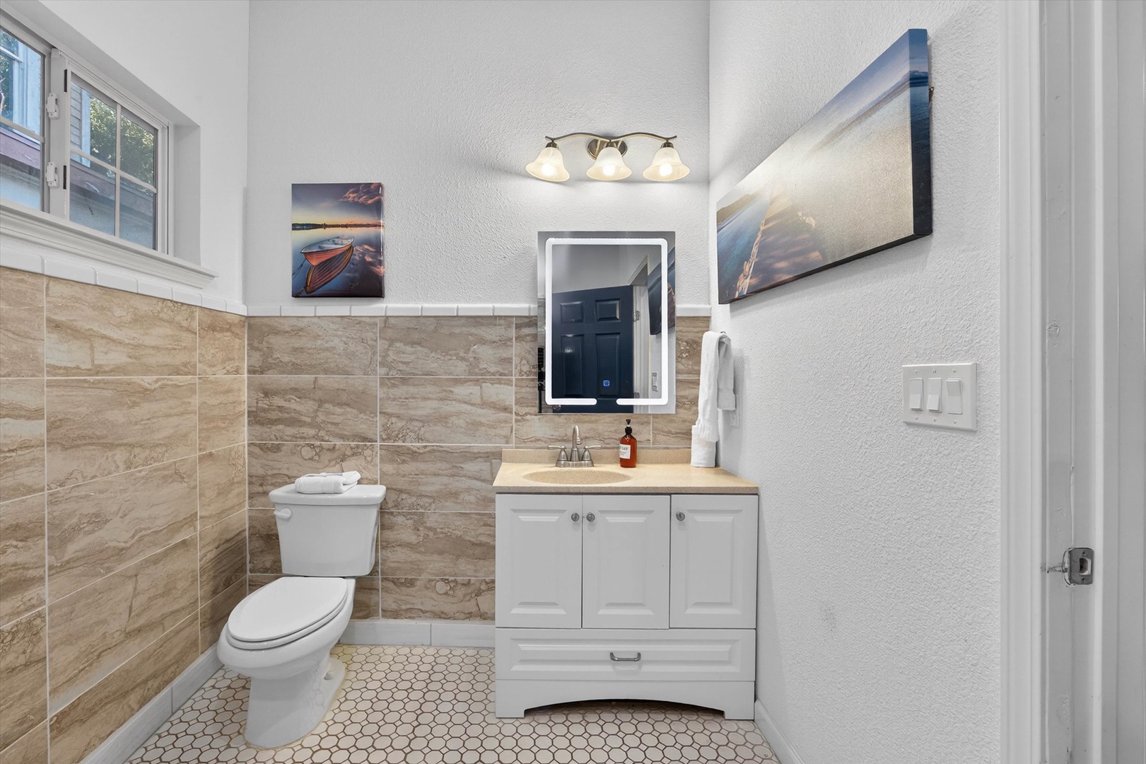 Refresh in this stylish shared bathroom featuring warm marble tiling, LED-lit mirror, and modern fixtures for your comfort.