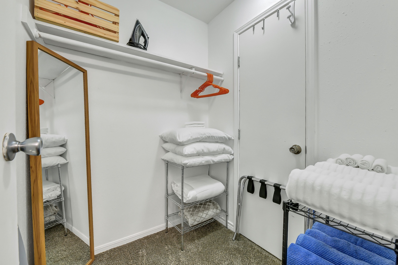 Organized closet with linens, iron and full-length mirror