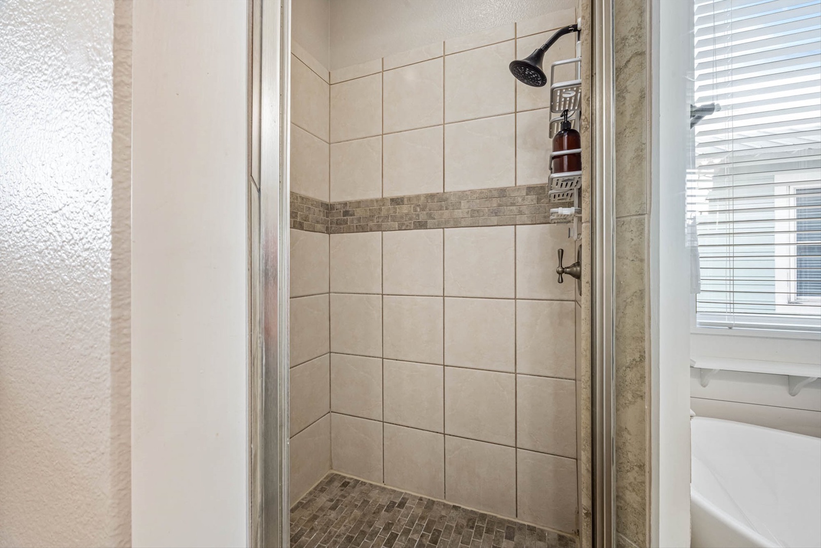 Shower with rainfall head and built-in storage for essentials.