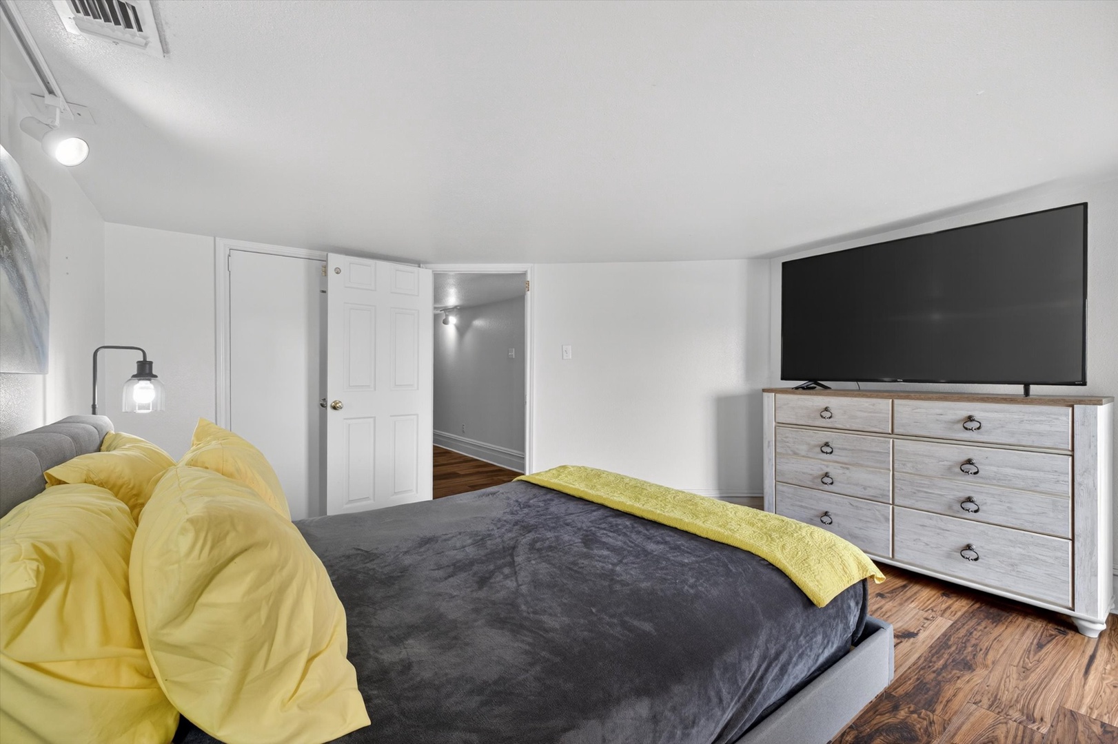 Modern bright bedroom with TV and warm wood floors.