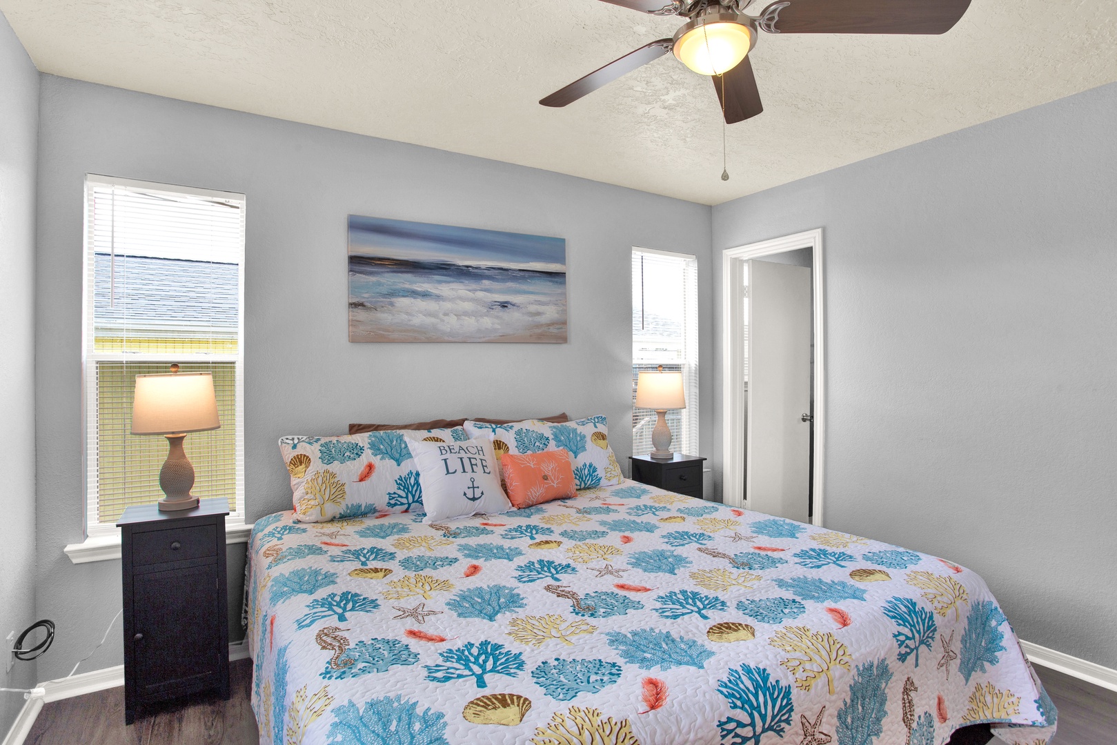 Drift off beneath a ceiling fan in your serene bedroom, where soft coastal hues and beach-inspired linens set the stage for a truly relaxing escape.