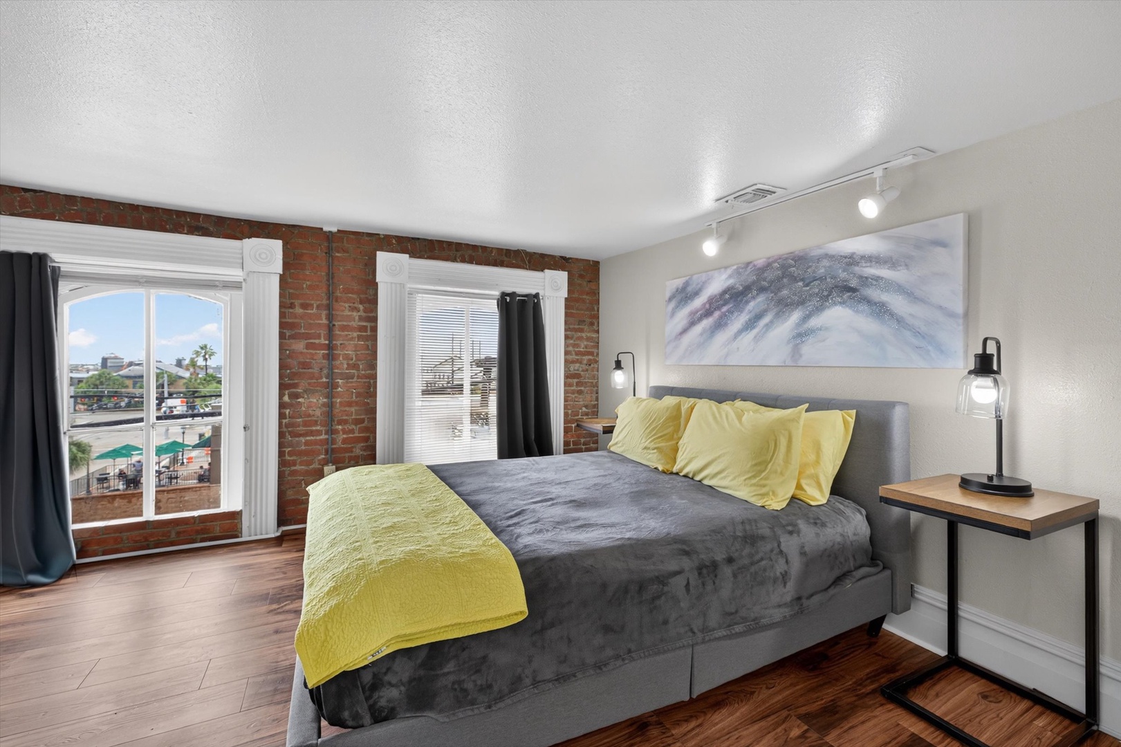 Stylish bedroom with brick, soft linens, and water views.