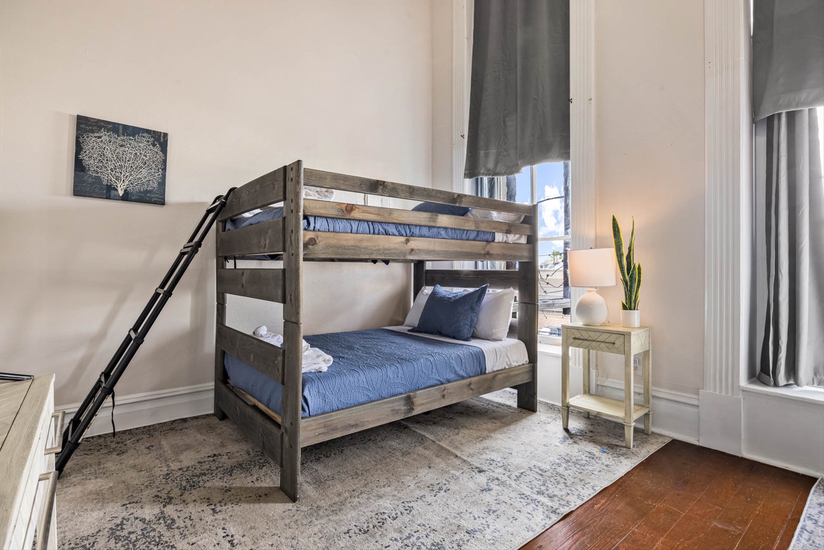 Cozy bunk room with wooden beds, blue linens, and modern touches.