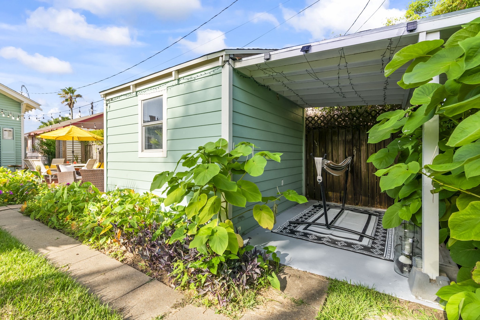 Charming cottage with lush plants and covered porch seating.