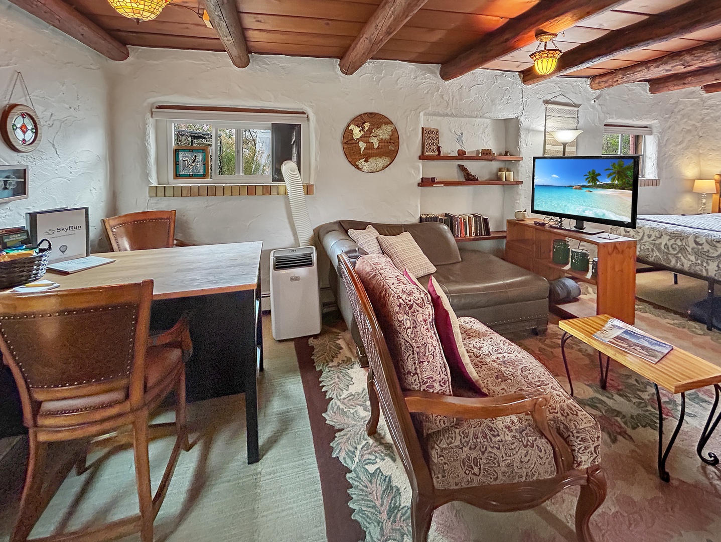 Relax in your charming living space featuring exposed wooden beams, a cozy leather sofa, and rustic dining area perfect for unwinding after exploring.