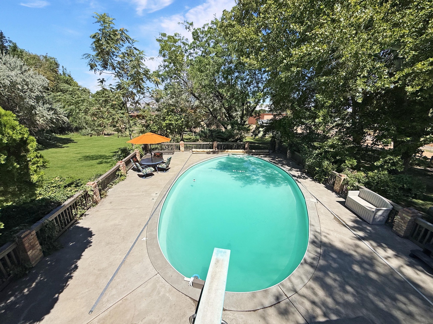 A private outdoor pool nestled in a spacious, tree-lined yard, complete with sun loungers and an umbrella for those lazy, sun-soaked afternoons.