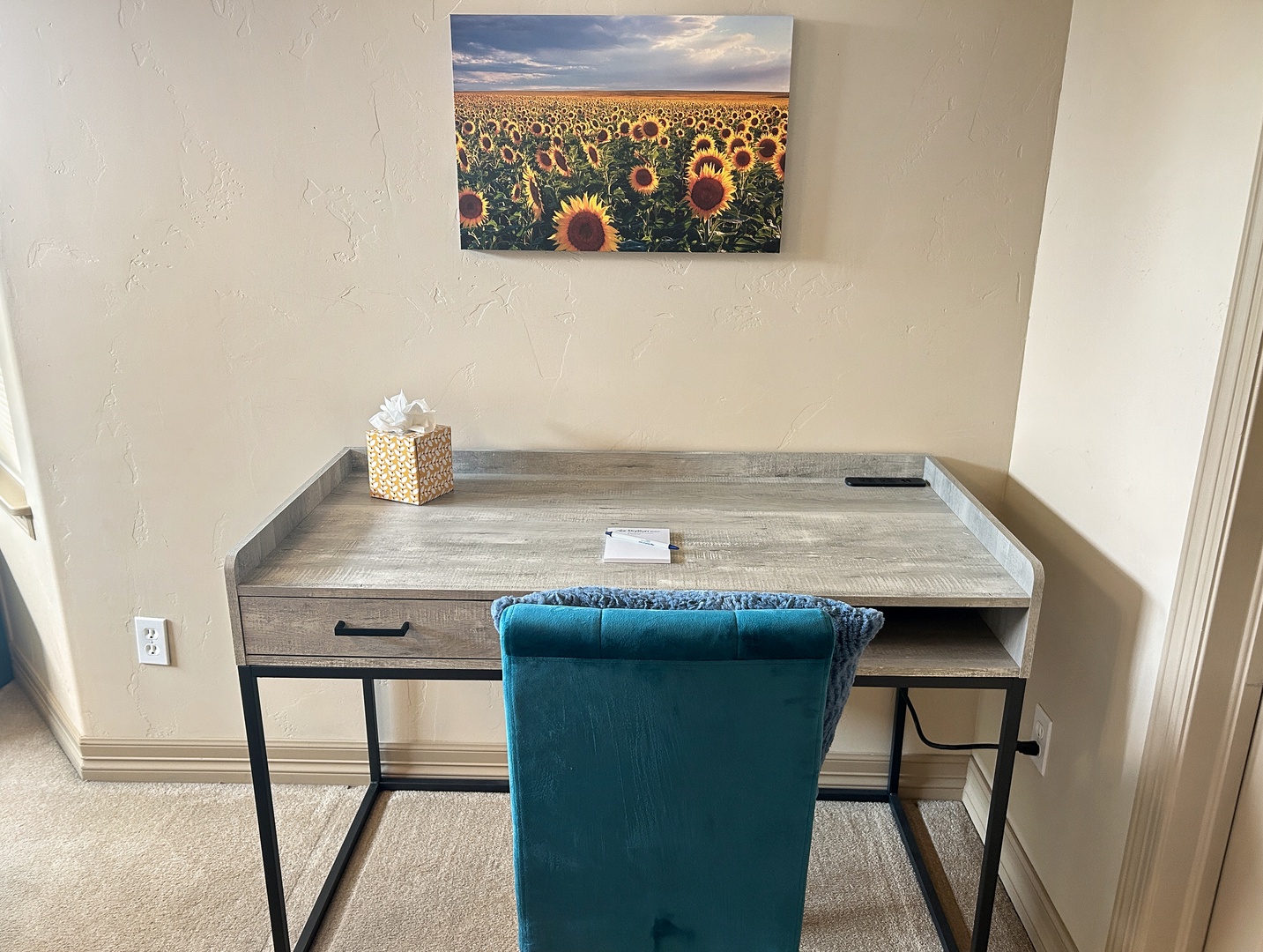 Your dedicated workspace awaits with a modern desk, comfortable seating, and inspiring sunflower artwork to brighten your productive moments.