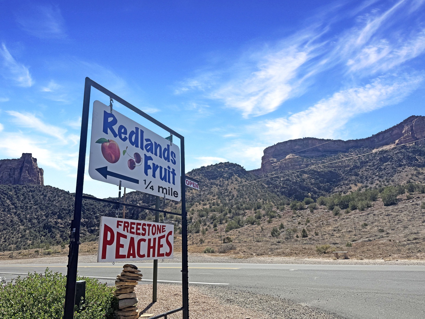 Dramatic red rock formations and desert hills frame the roadside landscape near this rural property.