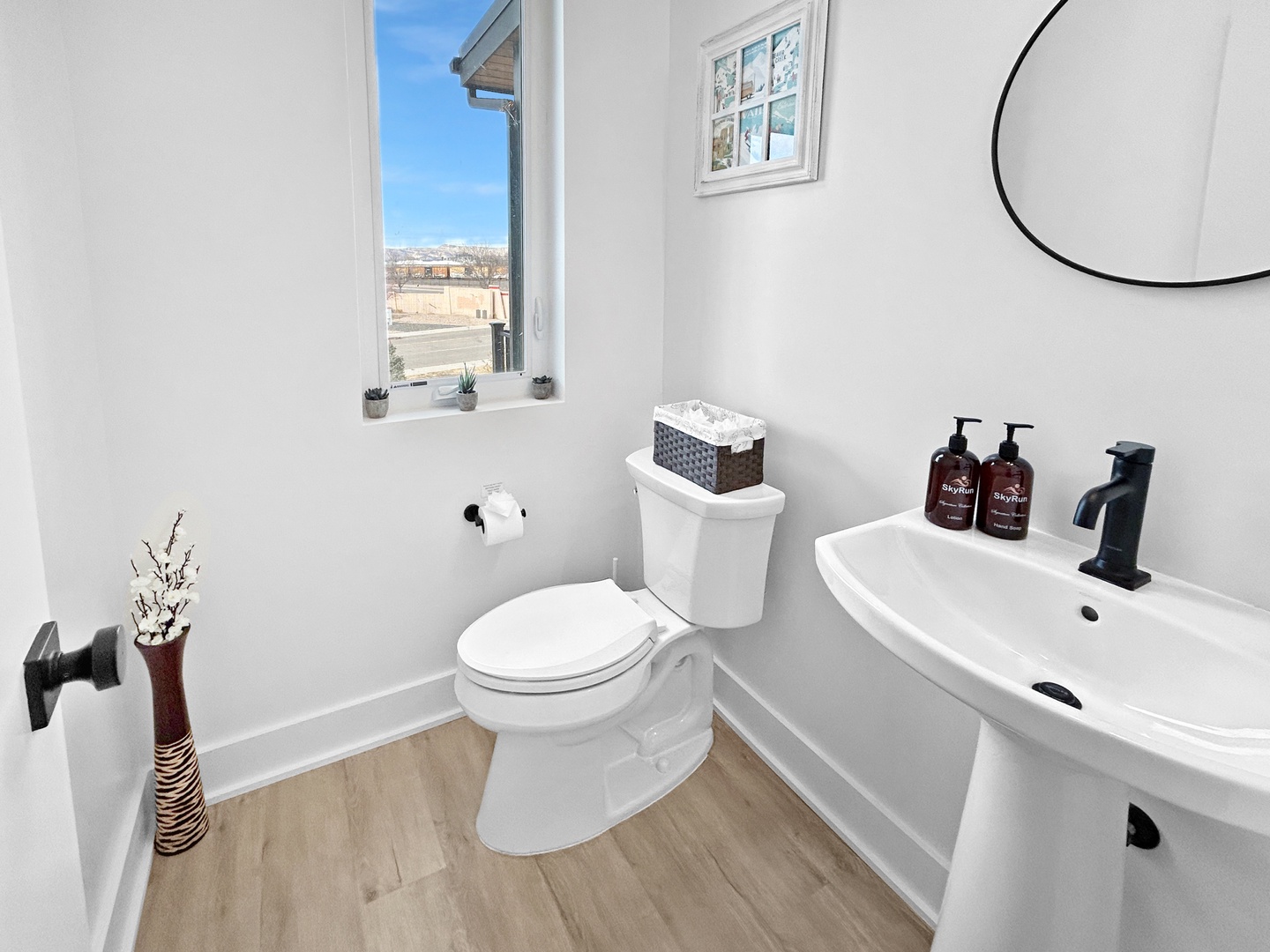 Step into your bright, modern powder room featuring crisp white fixtures and warm wood floors for your comfort.