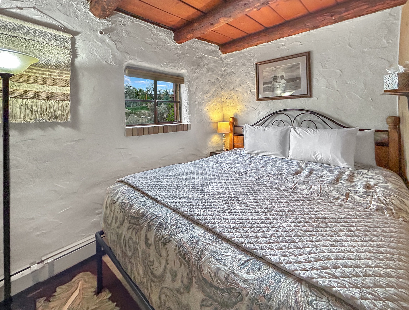 Drift off to sleep in this charming adobe bedroom with thick walls, exposed beams, and soft lamplight creating your perfect retreat.