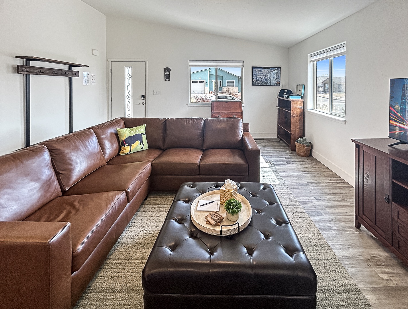 Sink into this luxurious leather sectional and unwind while enjoying natural light streaming through multiple windows in your spacious living room.