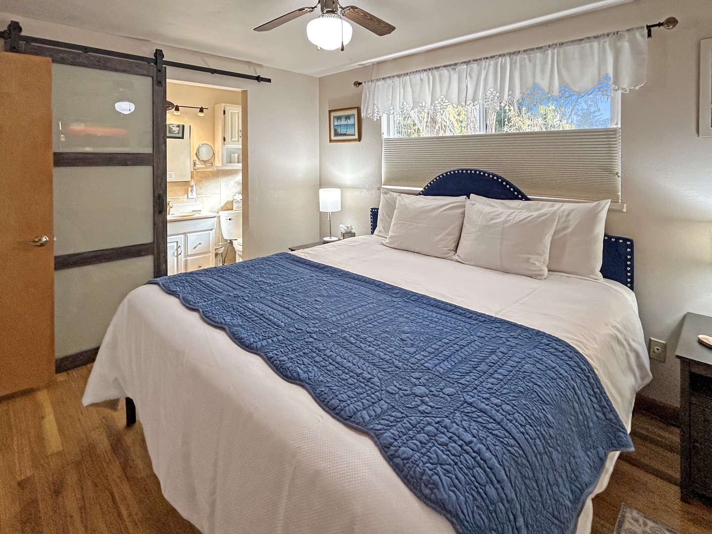 Cozy bedroom with plush king bed and soft natural light and private en suite full bathroom.