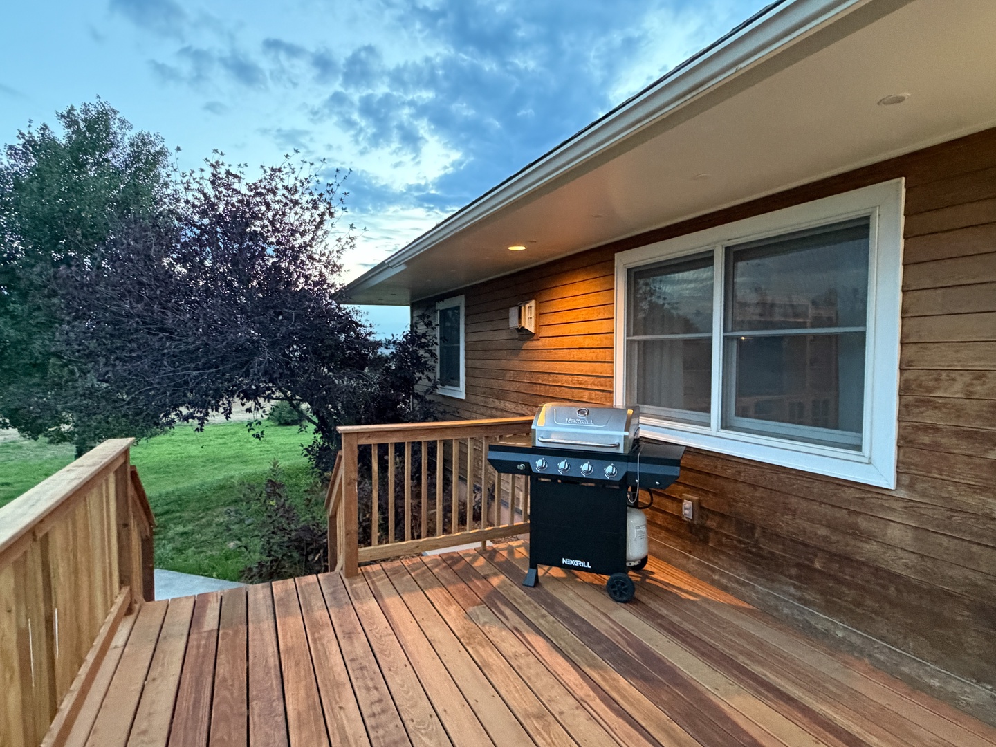 The deck features a gas grill ready for your outdoor cookouts, with a scenic background for a peaceful setting.