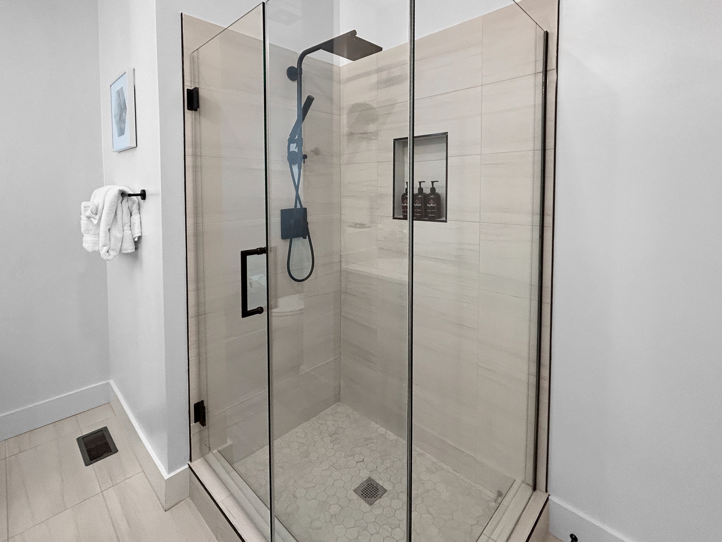 Step into your sleek glass-enclosed shower with rainfall head and built-in niche—pure luxury awaits your refreshing escape.