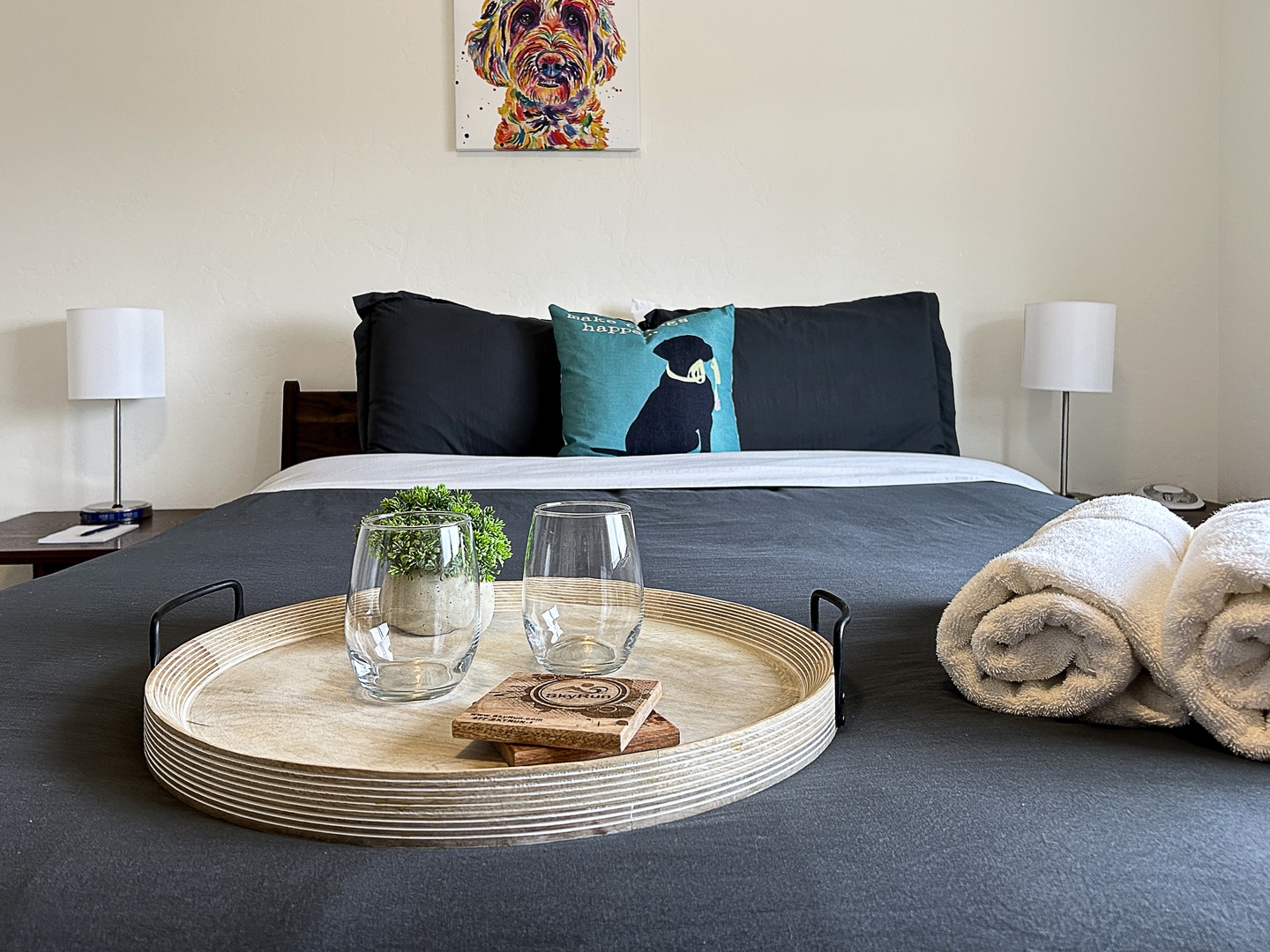 Settle into your cozy bedroom with plush towels, thoughtful touches, and charming dog artwork creating a welcoming retreat.