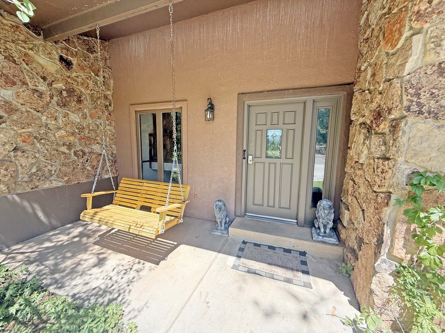 The welcoming front entrance greets you with rustic stone walls and a charming yellow porch swing.