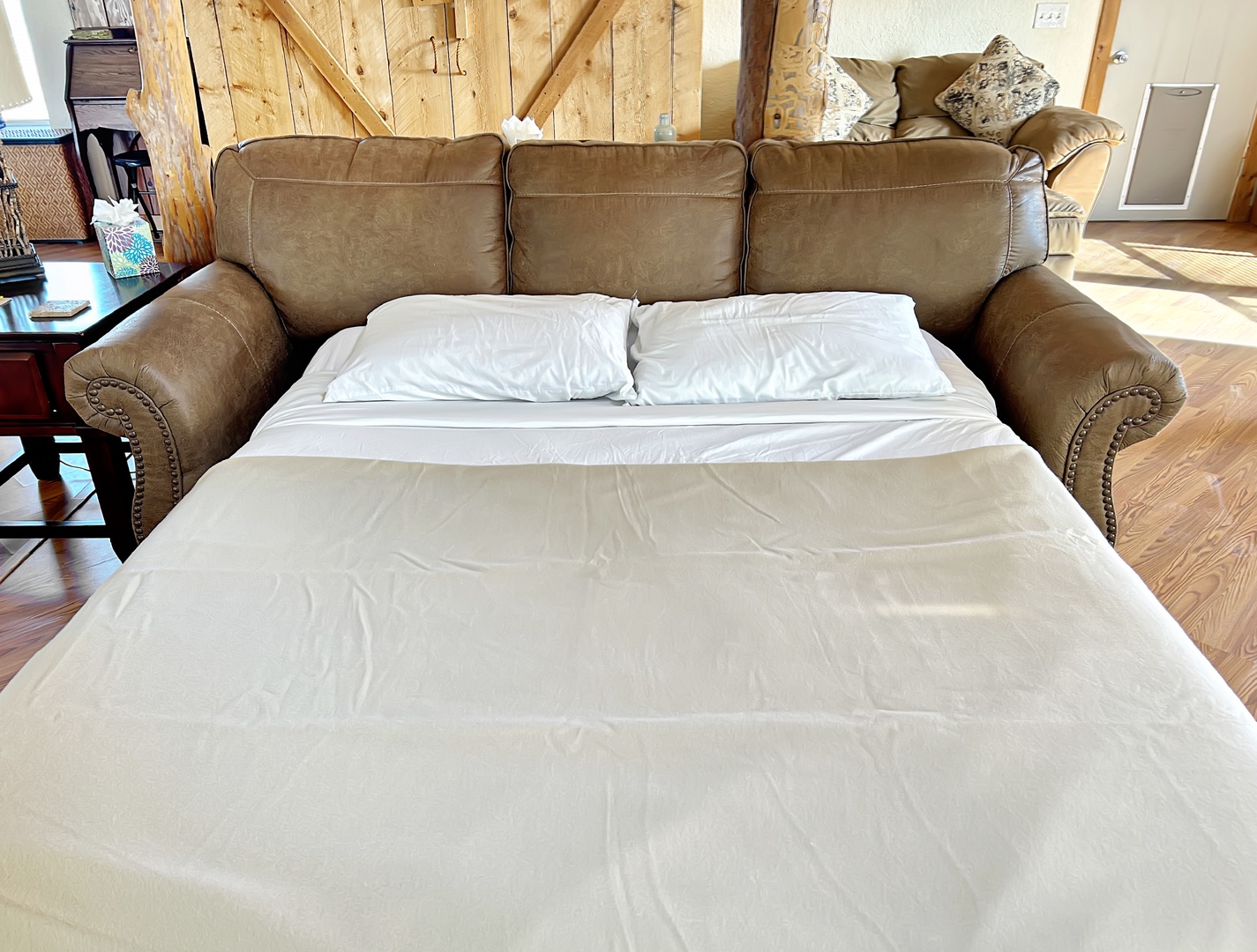 Your comfortable leather sofa transforms into a cozy queen bed, perfect for relaxing in the rustic cabin atmosphere.