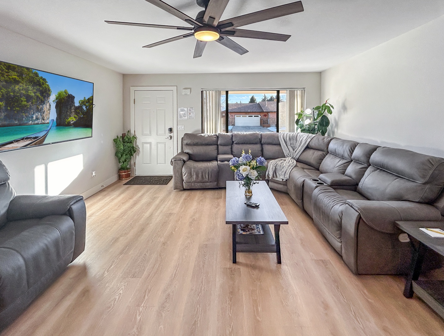 Relax in your spacious living room with plush sectional seating, modern ceiling fan, and large TV for movie nights.