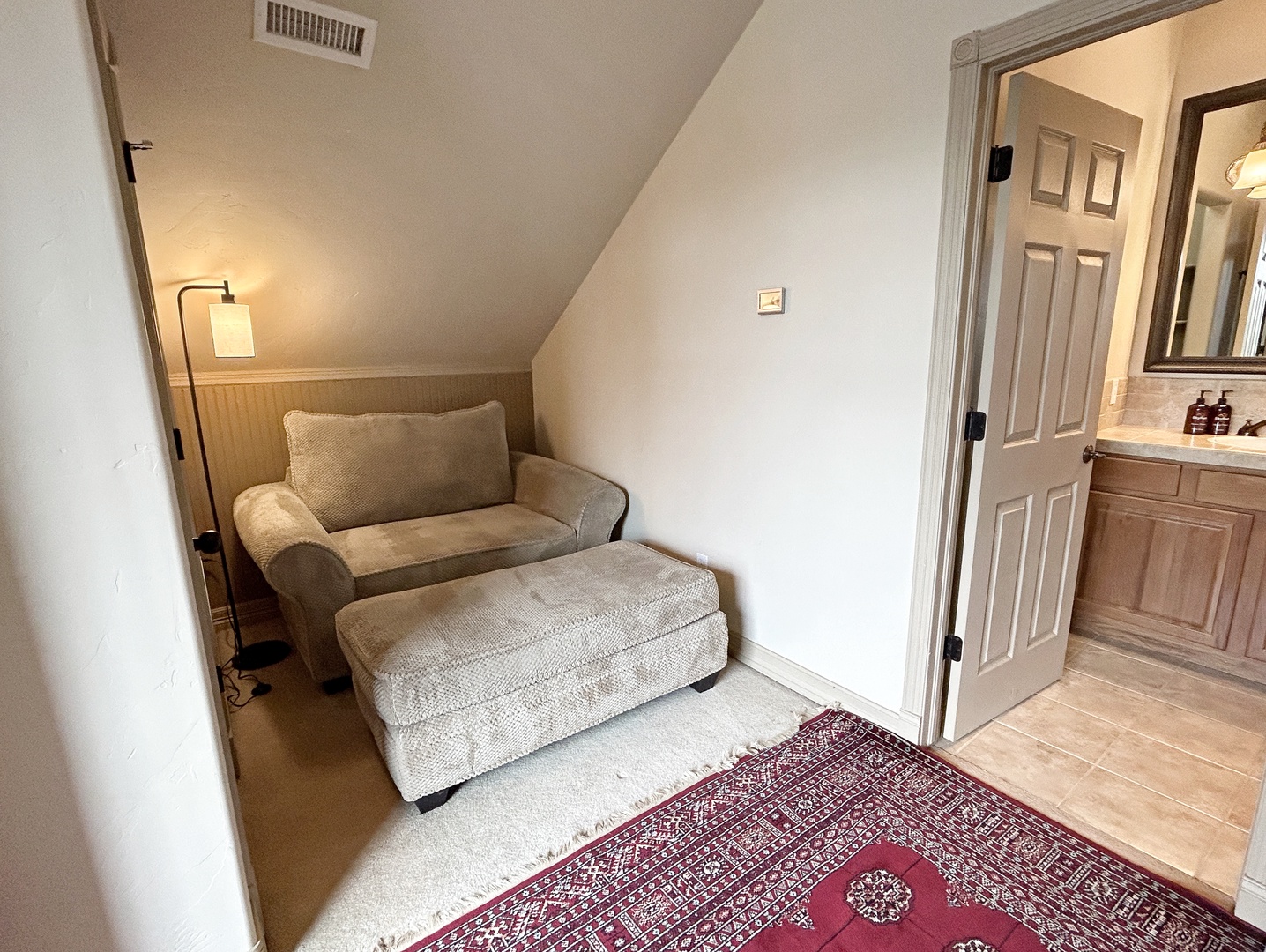 Sink into your cozy reading chair with ottoman, perfectly positioned by the warm bedside lamp for evening relaxation.