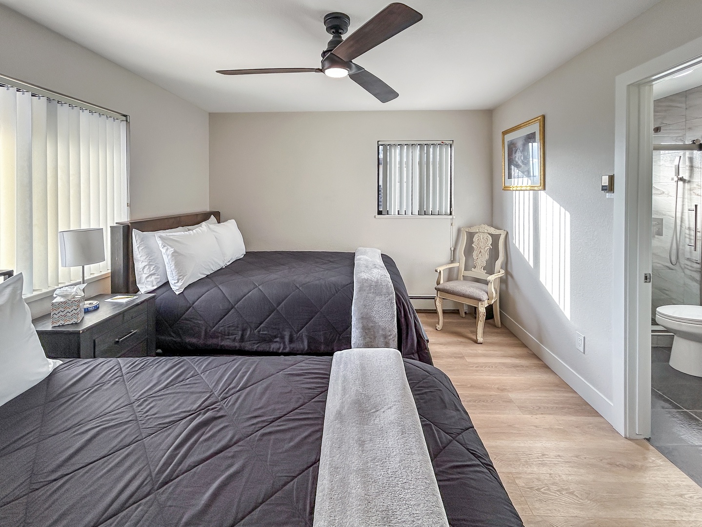 Unwind in your peaceful bedroom featuring two cozy beds, a gentle ceiling fan, and convenient ensuite bathroom access for ultimate comfort.