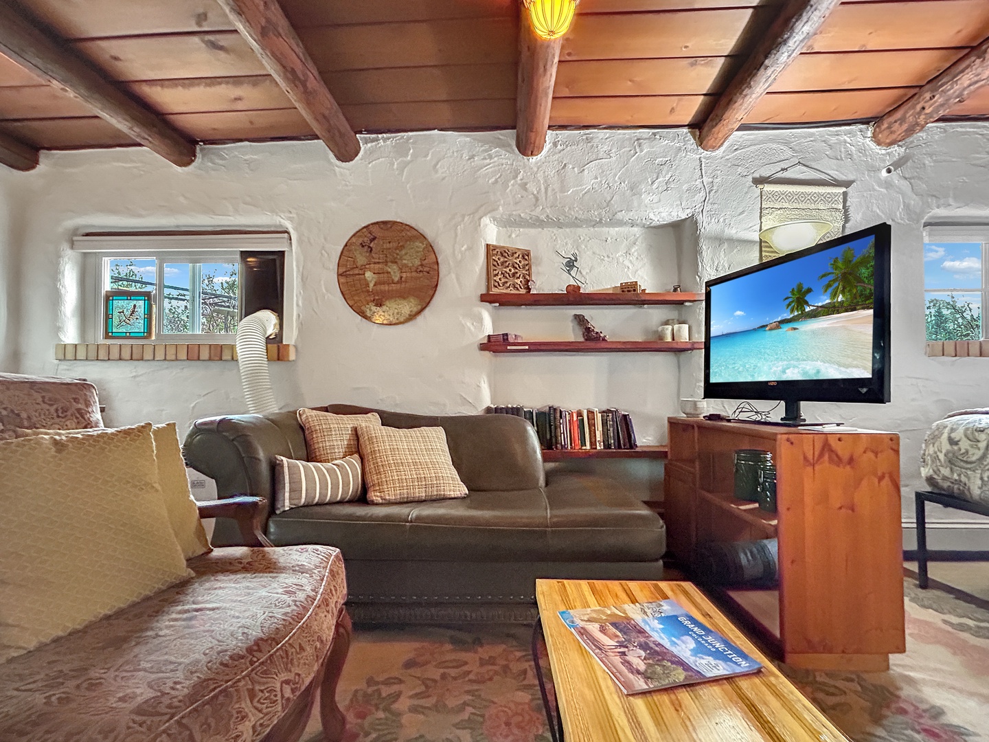 Unwind in your cozy living space featuring rustic wood beams, comfortable seating, and modern entertainment for perfect vacation relaxation.