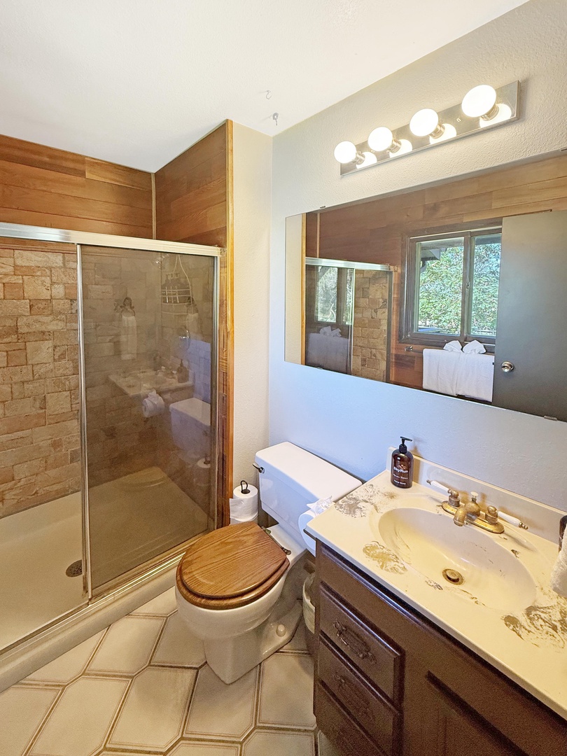 Your private bathroom features warm wood tones, a walk-in shower, and natural light streaming through the window—perfect for refreshing after a day of adventure.