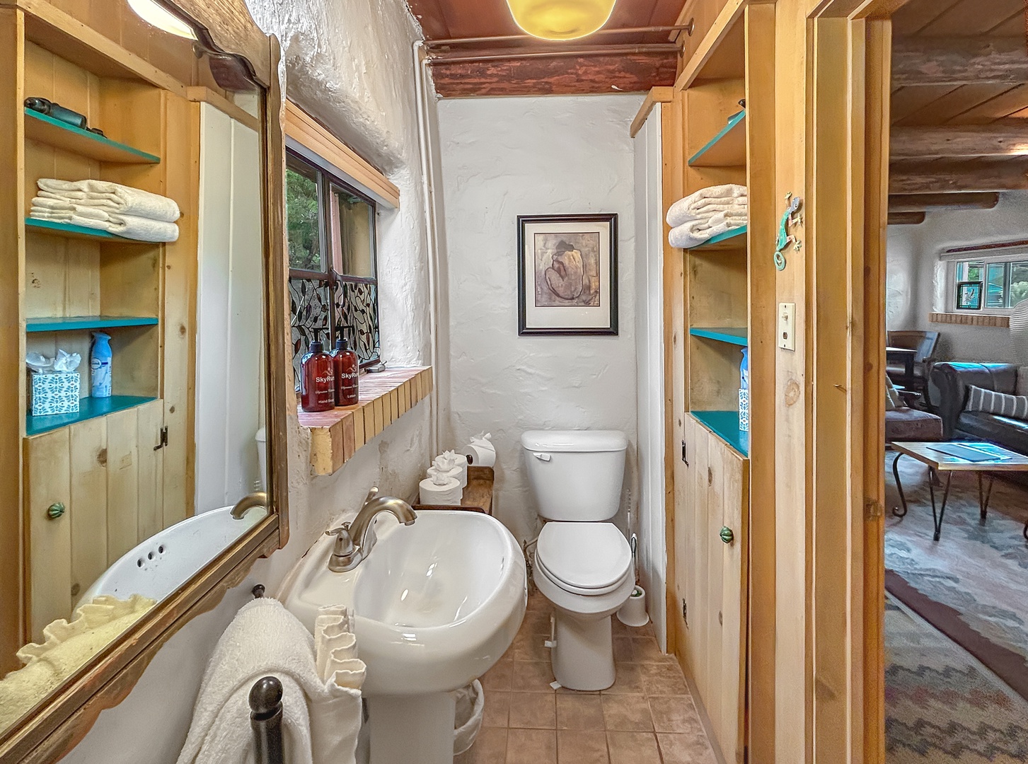 Step into your charming rustic bathroom featuring warm wood shelving stocked with fresh towels and thoughtful amenities for your comfort.