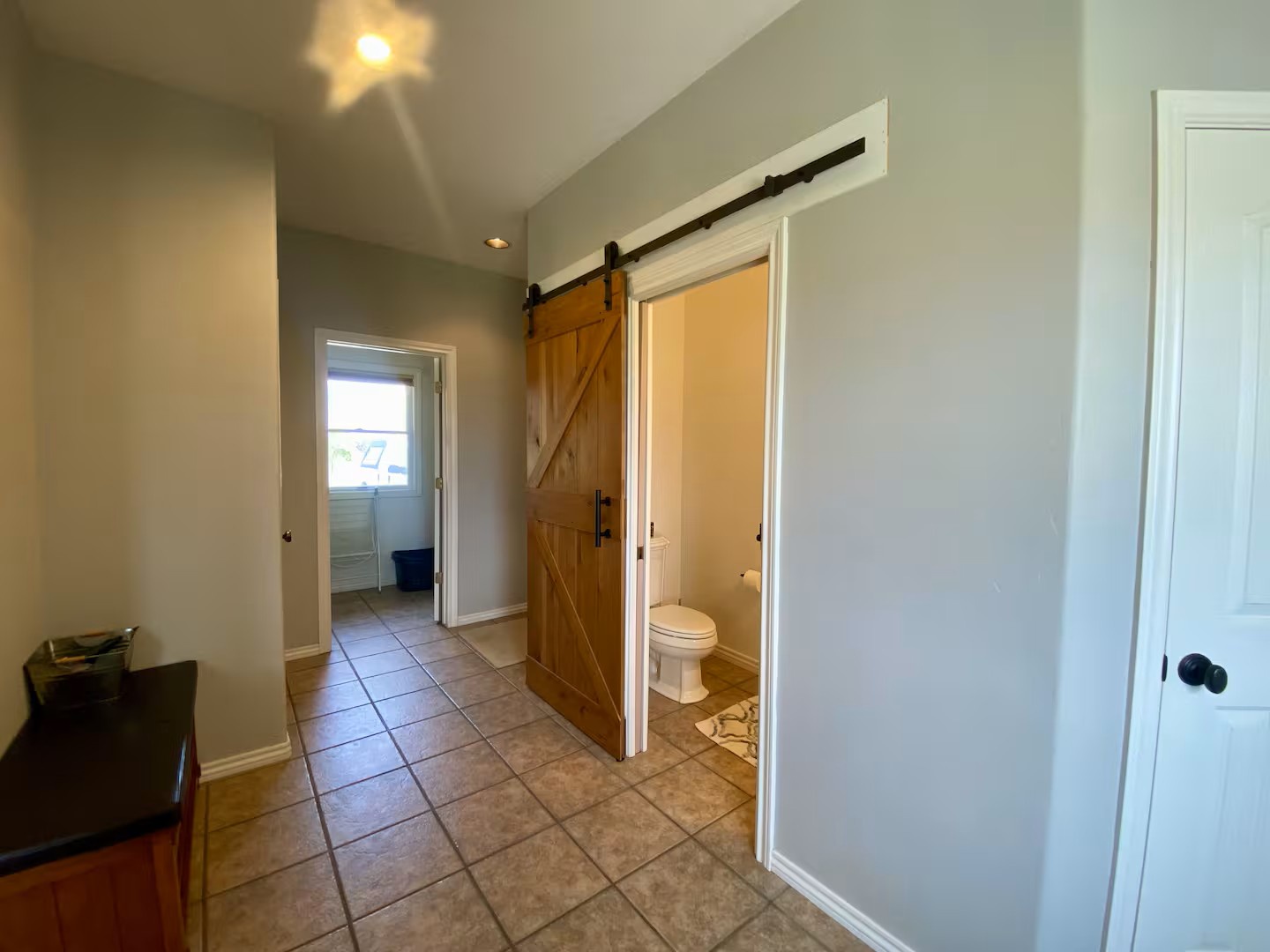 Your hallway features charming rustic barn-style doors leading to a well-appointed half bathroom and laundry room.