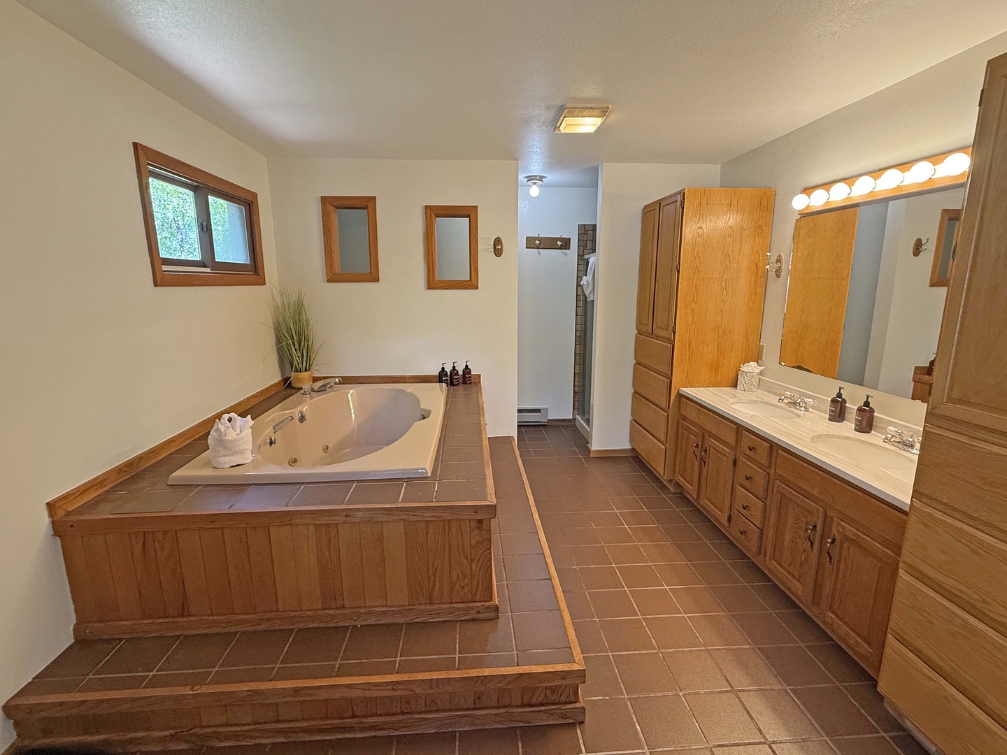 Unwind in your spacious bathroom featuring a jetted tub, dual vanities with ample storage, and warm wood accents throughout.