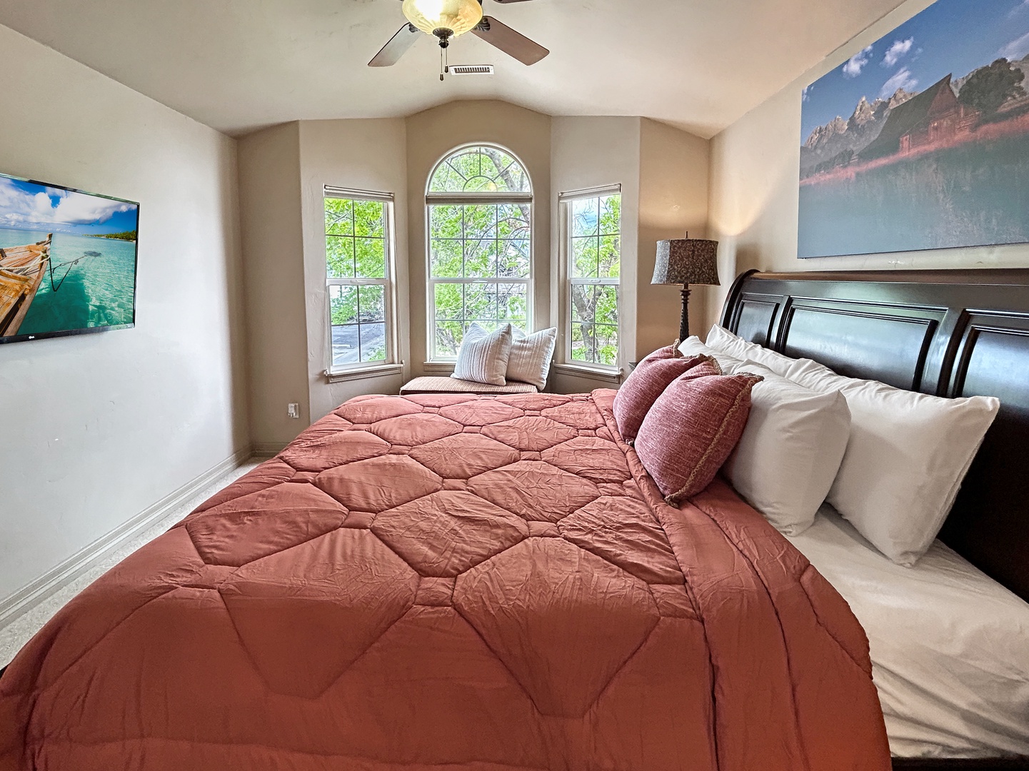 Wake up in this serene bedroom with stunning arched windows and natural light streaming across your comfortable king bed.