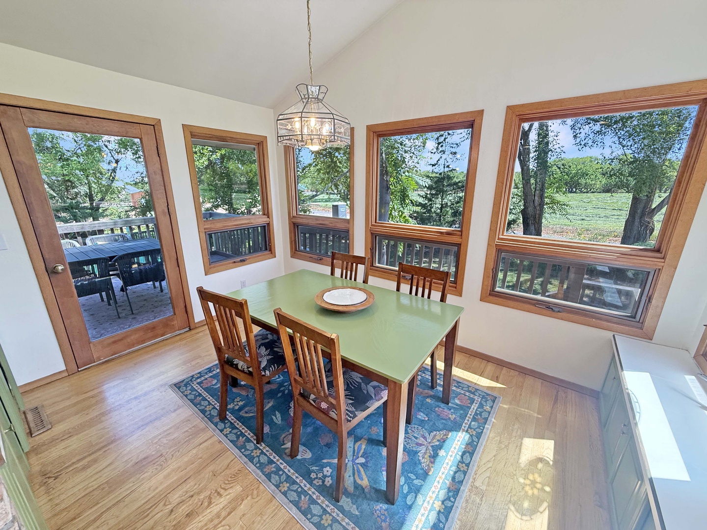 Gather at your sunlit dining table, surrounded by windows that frame peaceful garden views and open onto a spacious deck perfect for al fresco meals.