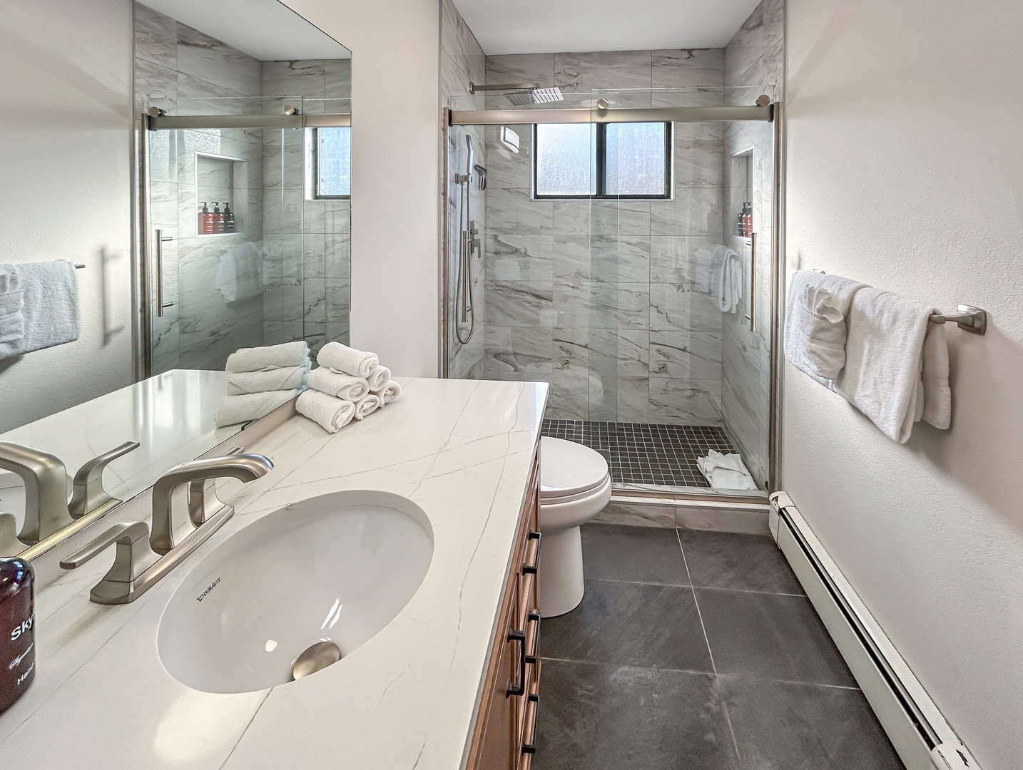Indulge in your spacious modern bathroom with rainfall shower, premium fixtures, and plush towels.