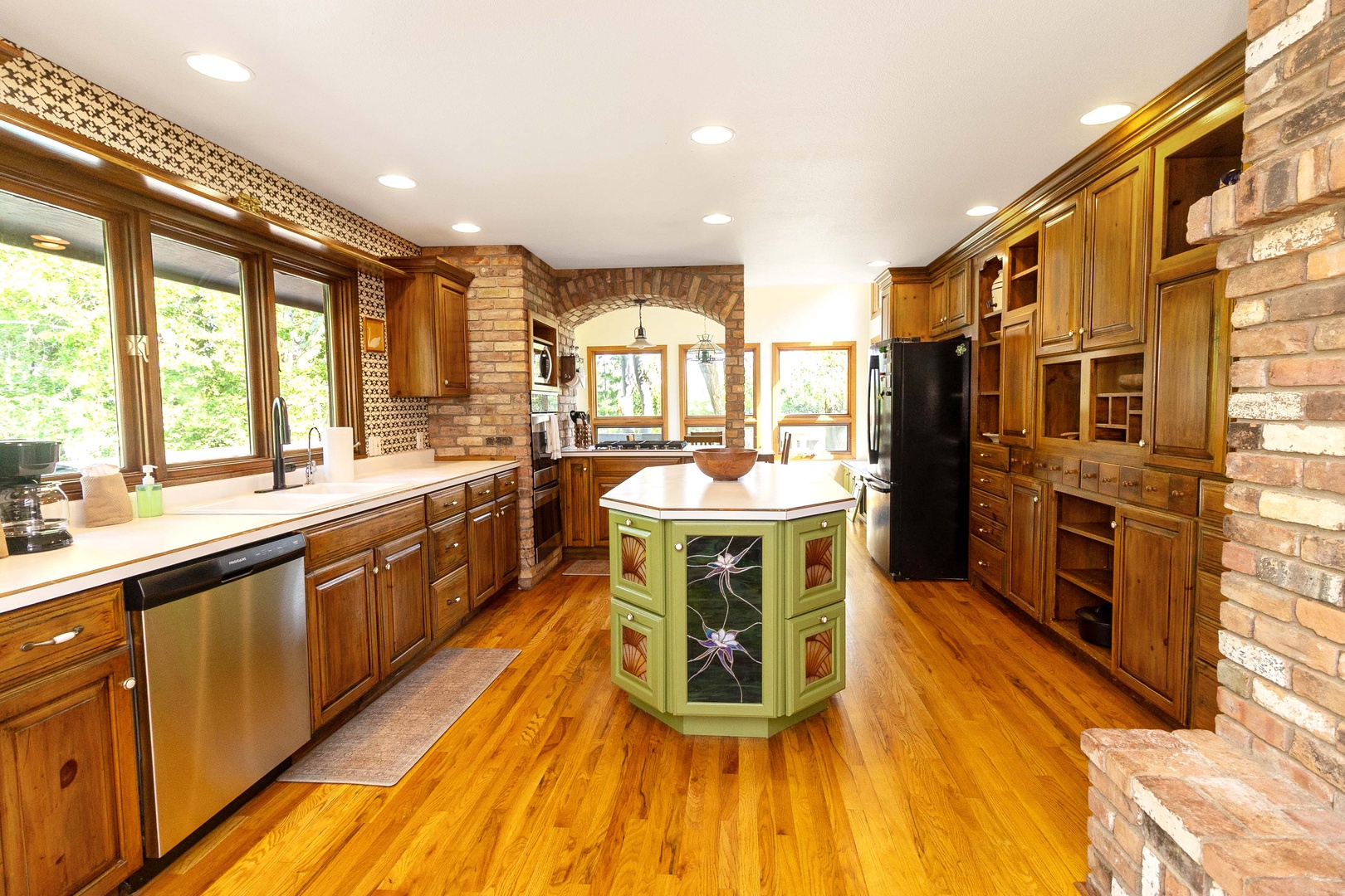 Your gourmet kitchen awaits with rich wood cabinetry, a charming center island, and warm brick archways that invite culinary creativity and gathering.